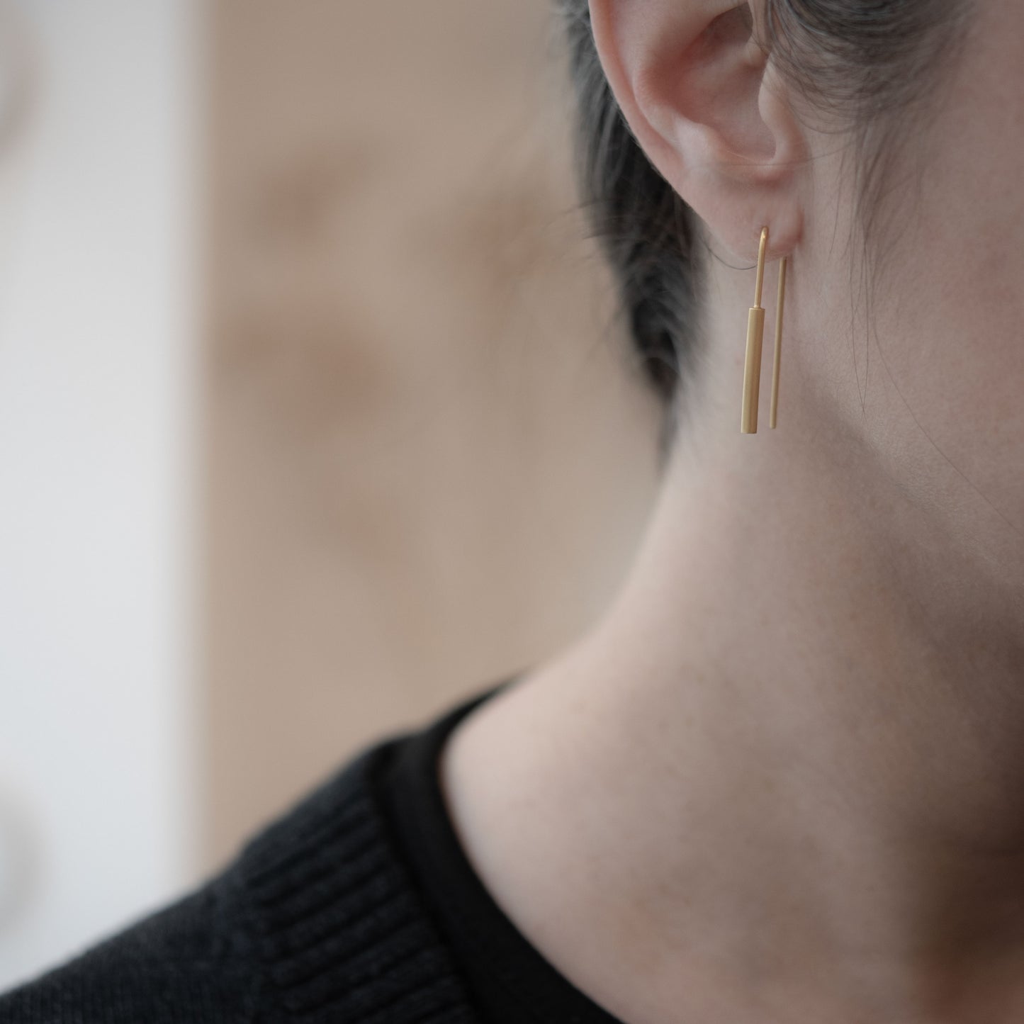 Boucle d’oreille pendantes en vermeil portée à design minimaliste et cylindrique en argent plaqué or 24k, finition mate, bijou délicat au style contemporain