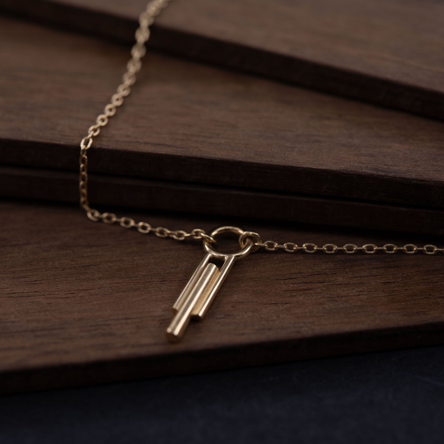 Collier Art Déco en vermeil posé sur bois foncé empilé, bijou minimaliste fait main parisien