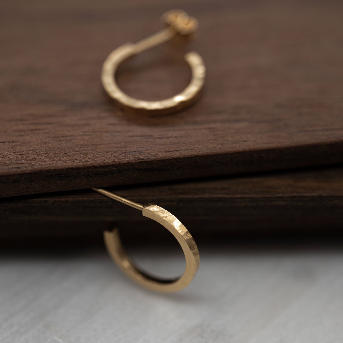 Halered gold hoop earrings on a wooden surface