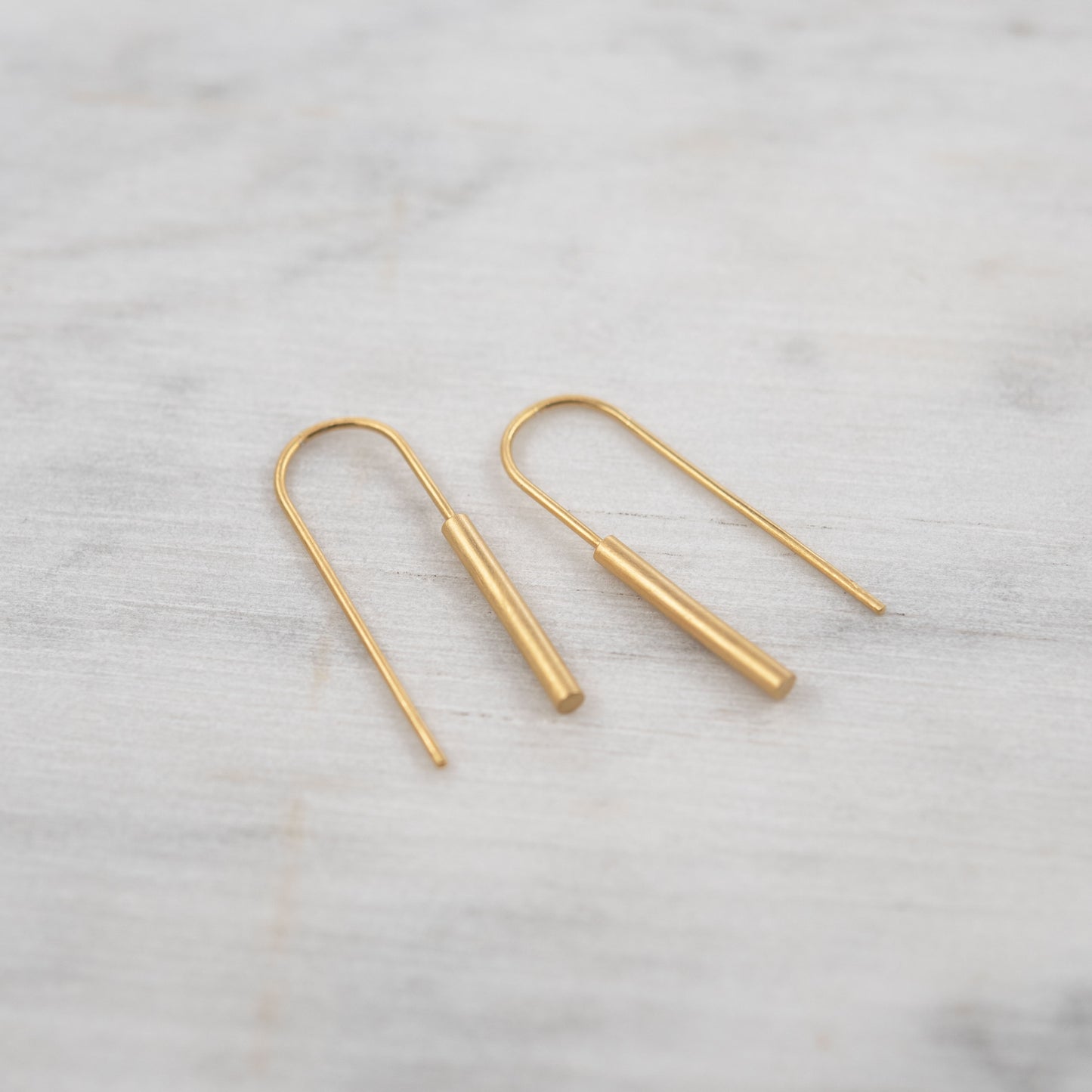 Minimalist gold vermeil threader earrings on white marble