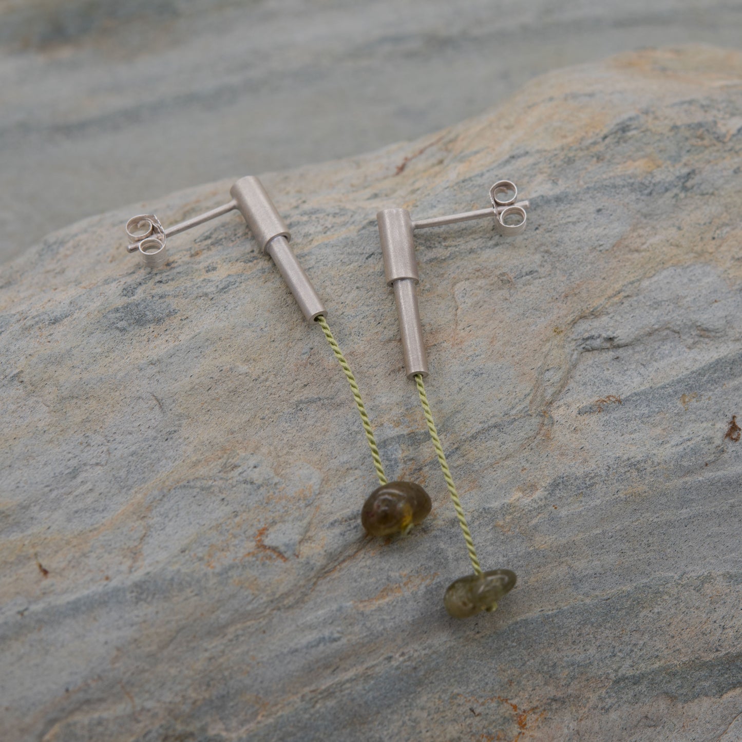 Pair of 37 mm length pendant earrings handmade in sterling silver tube with a light green silk cord threaded through the center for hanging a green garnet stone. Designed and crafted by hand in Paris by A g J c duo.