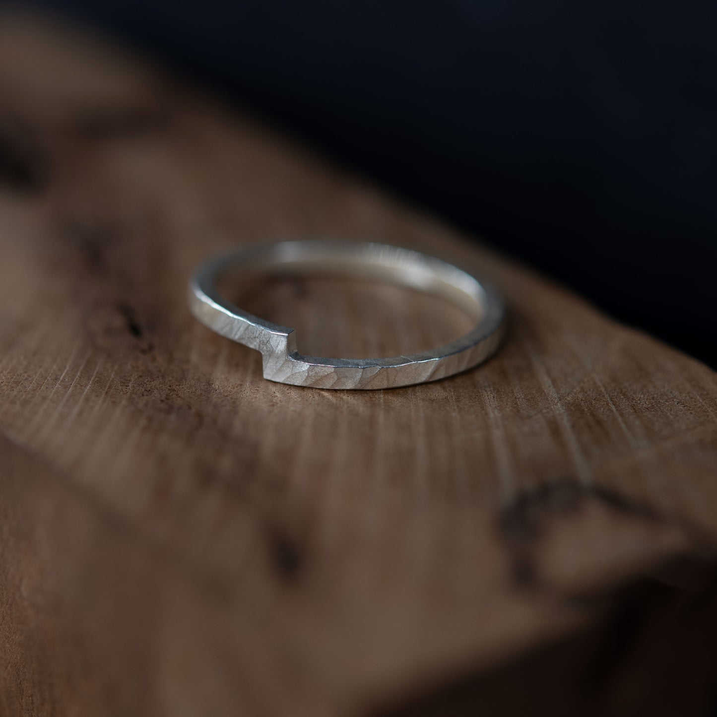 Bague en argent sterling martelée posée sur une surface en bois, avec un design unique symbolisant l'union de deux éléments. Cette bague minimaliste présente une encoche distinctive qui incarne la connexion et l'harmonie, idéale comme alliance, bague de fiançailles ou accessoire quotidien significatif. Un bijou artisanal moderne et intemporel.