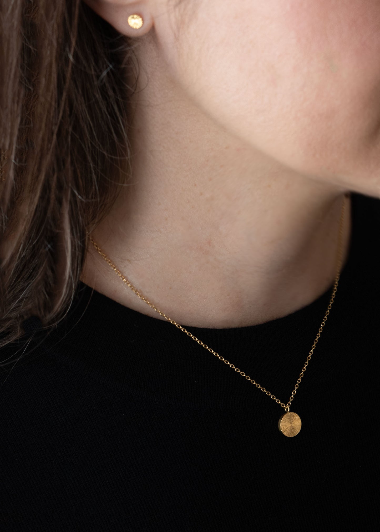 8. Modèle portant collier médaille éclat de soleil en or gravé à la main, bijou artisanal élégant et discret de Paris.