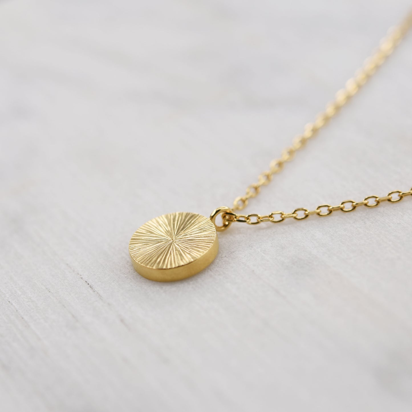 Détail collier médaille ronde en vermeil or parfait pour un cadeau fait main raffiné et symbolique pour femme.