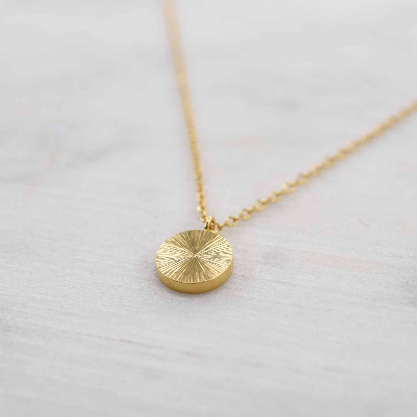 Vue de côté collier pendentif lumineux comme un éclat de soleil en vermeil doré. Bijou minimaliste artisanal de Paris.