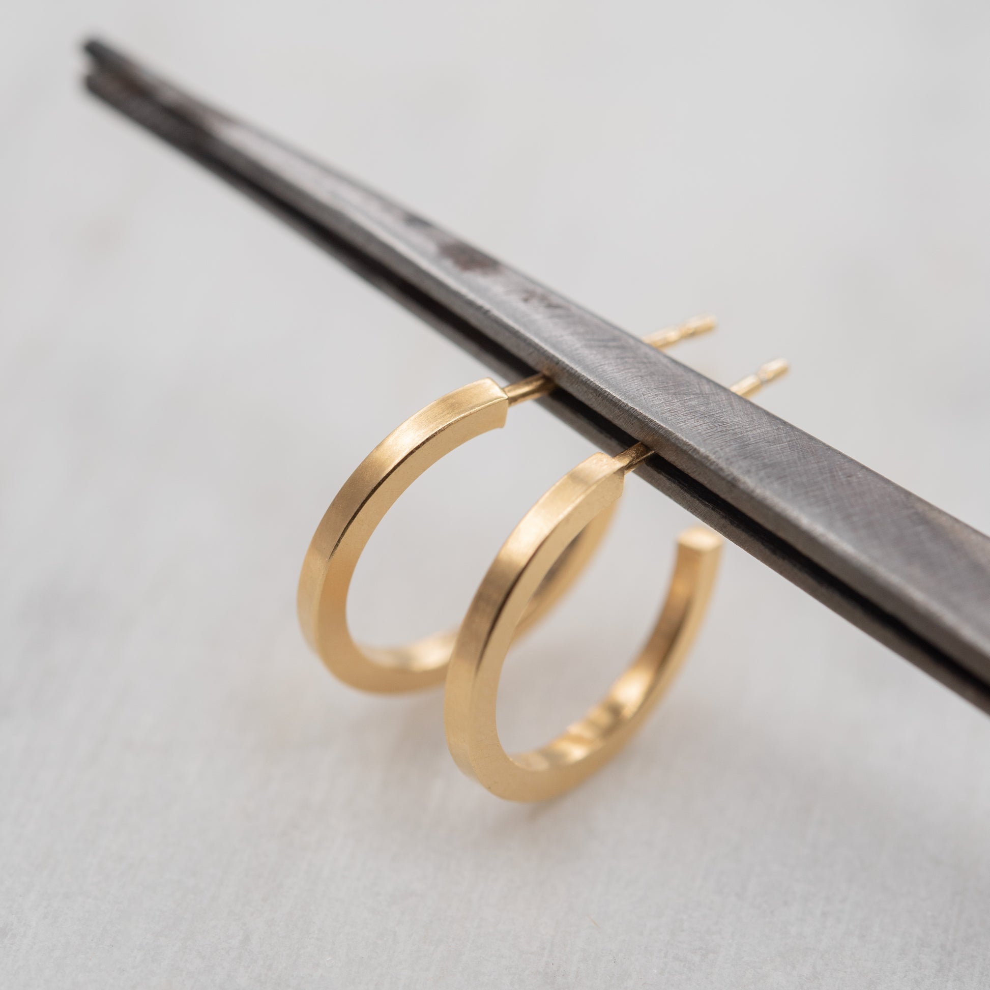 Créoles fines en vermeil or posées sur fond clair, bijou minimaliste et artisanal fabriqué à Paris.