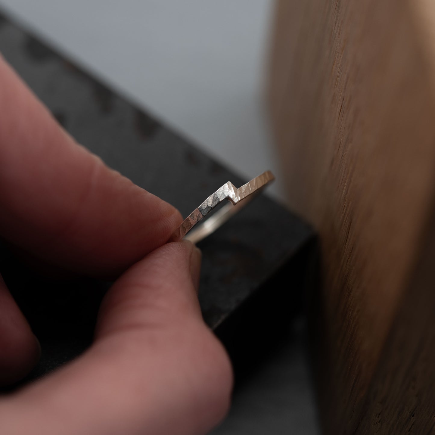 Close-up of a hand holding a hammered sterling silver unity ring, featuring a unique notch design that symbolizes the merging of two elements. The ring's minimalist and modern style represents connection and harmony, making it suitable as a wedding band, engagement ring, or a meaningful everyday accessory. Handmade with attention to detail.