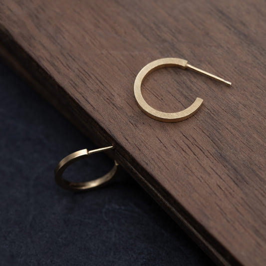 Paire de petites créoles en vermeil or 24k posées sur une planche en bois sombre, finition satinée, faites main à Paris.