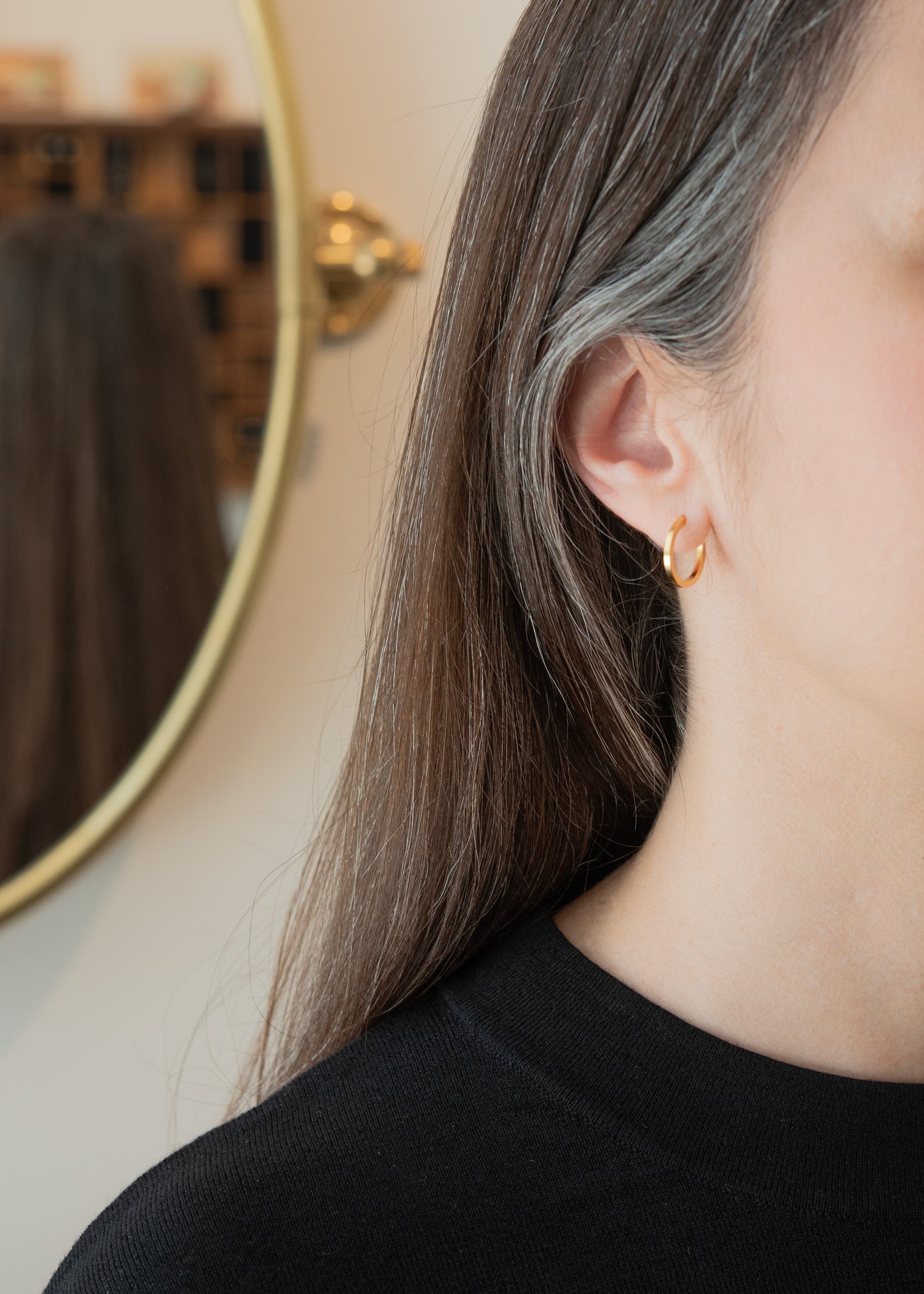 Close-up of a person wearing gold earrings with a blurred background