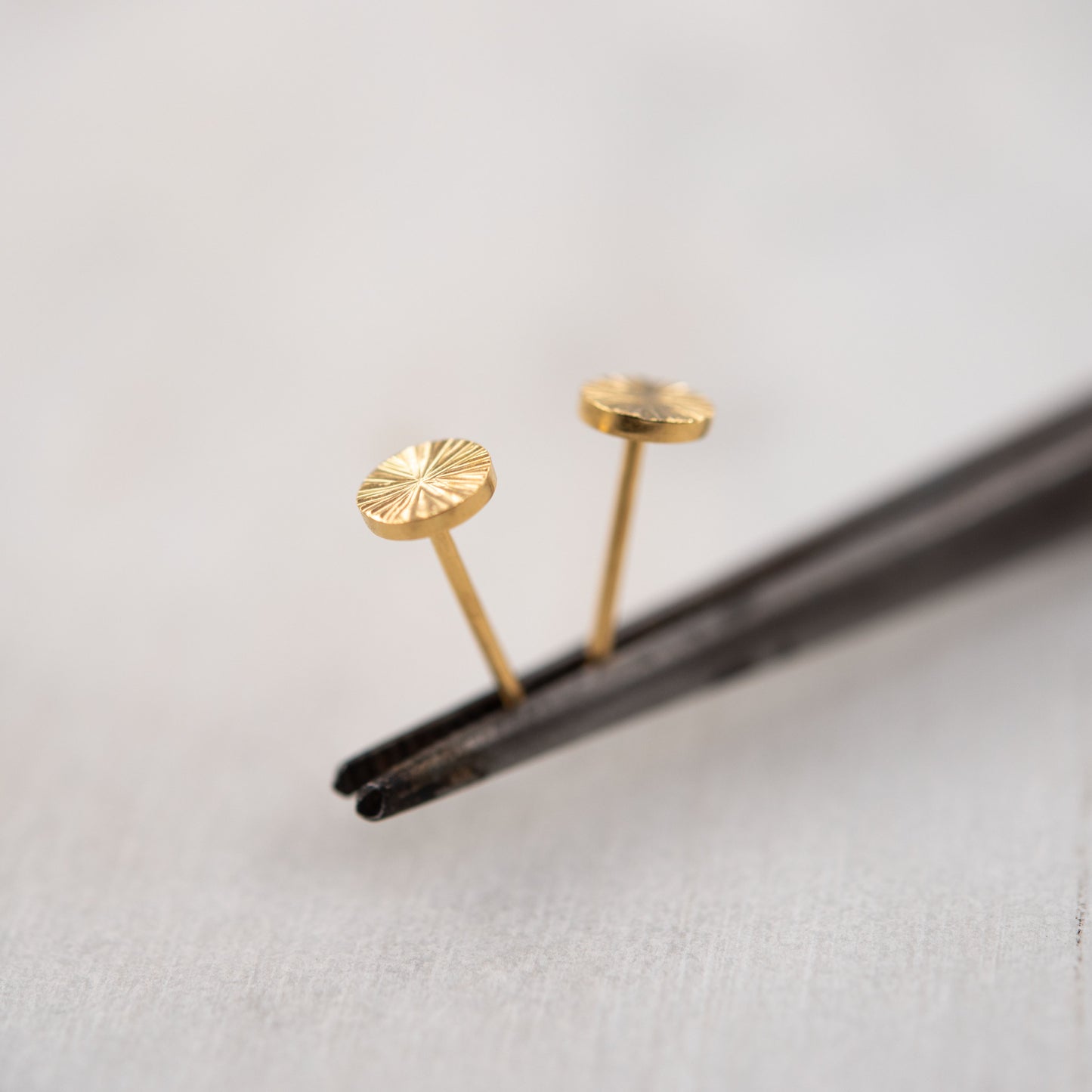 Close-up of small gold vermeil engraved stud earrings on white background – minimalist Paris handmade jewelry