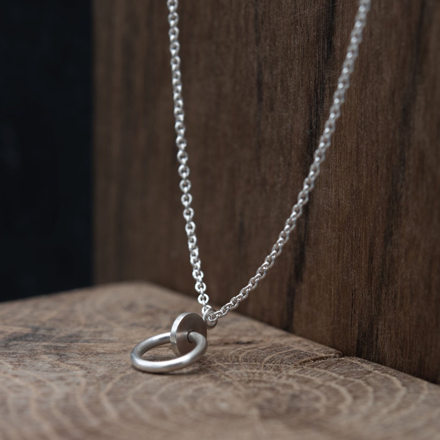 Close up of a circle and dot pendant necklace in sterling silver matte finished