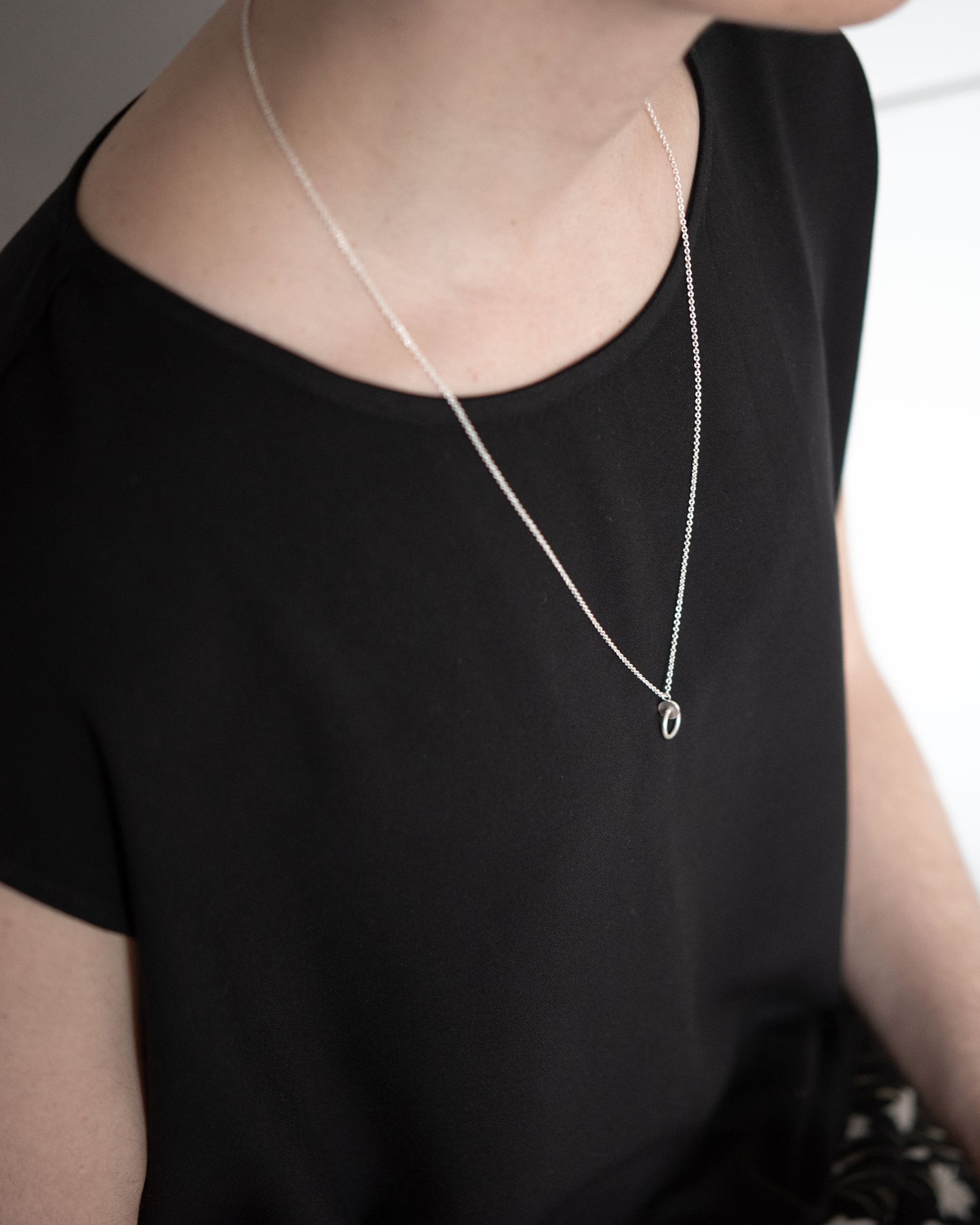 a woman with a dark skirt is wearing a circle and dot pendant necklace in sterling silver matte finished