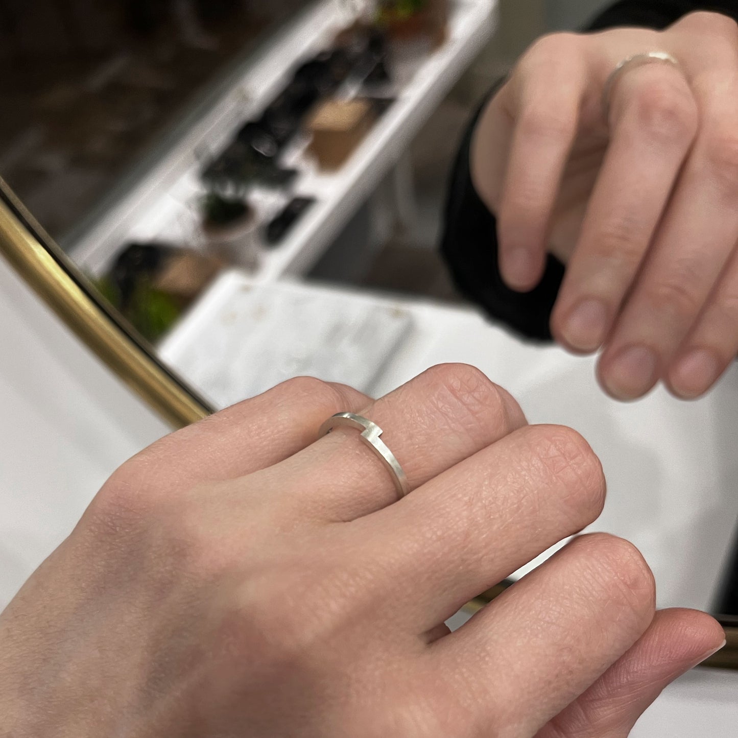A hand wearing a thin band silver ring in a small jewelry studio shop in Paris. 