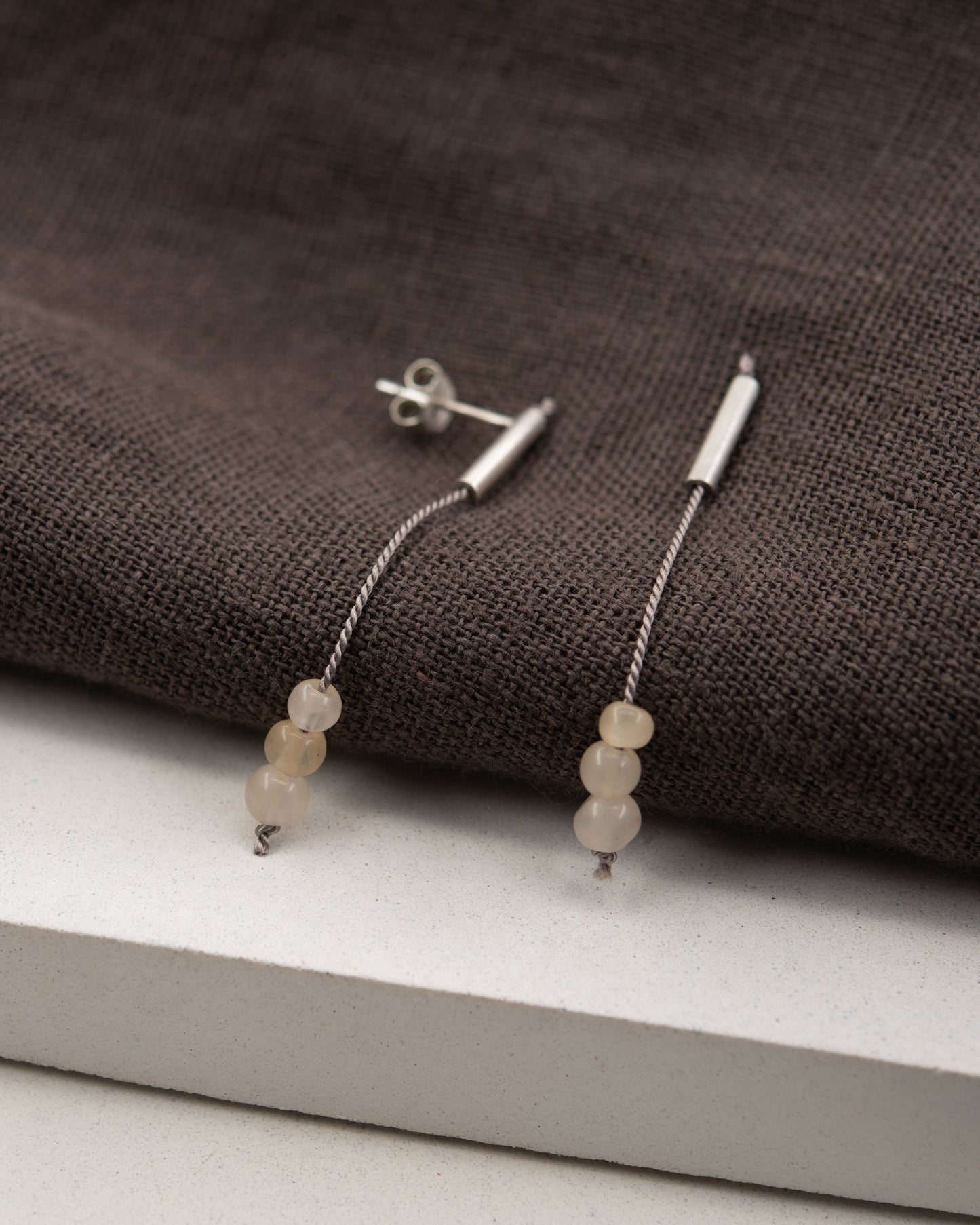 Pair of 42 millimeters length pendant earrings handmade in in Paris by A g J c  from  tube of matte sterling silver with a beige silk cord threaded through the center for hanging yellow quartz beads. 