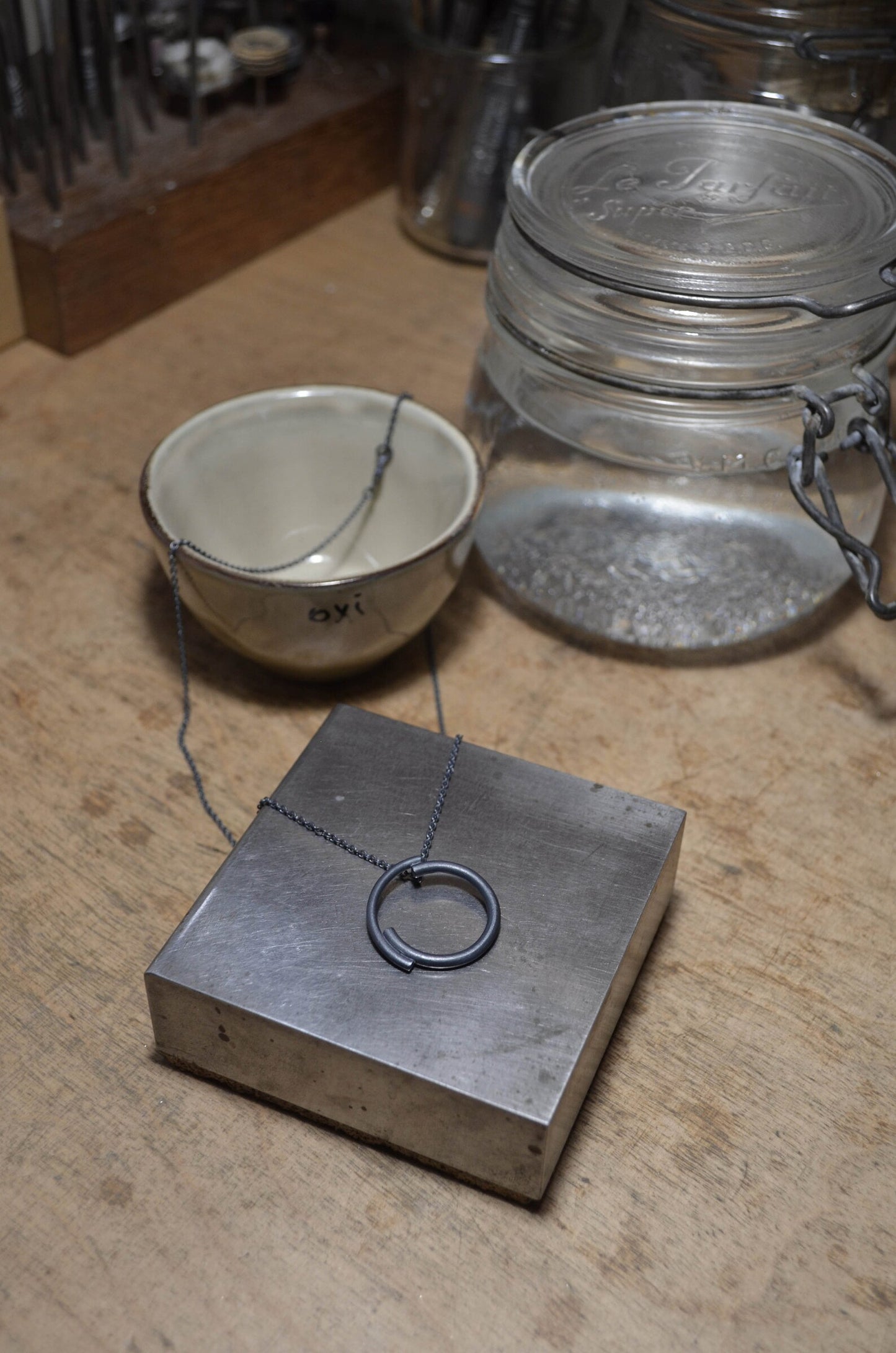 A jewelry bench showing an oxidized silver circle necklace of 22 milimeters of diameter