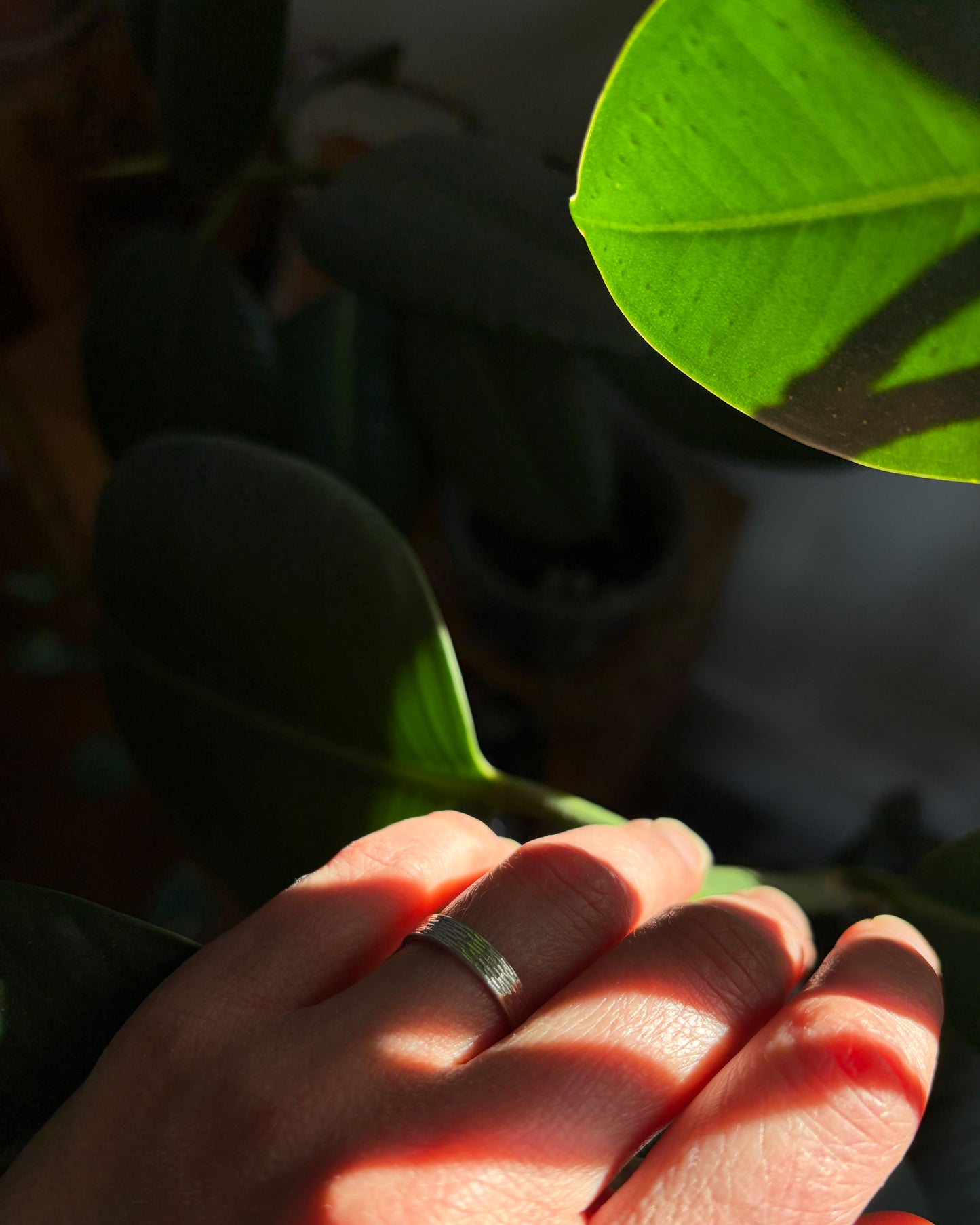 Bague Étincelles, alliance artisanale en argent avec relief gravé captant la lumière, portée au quotidien sur main féminine.