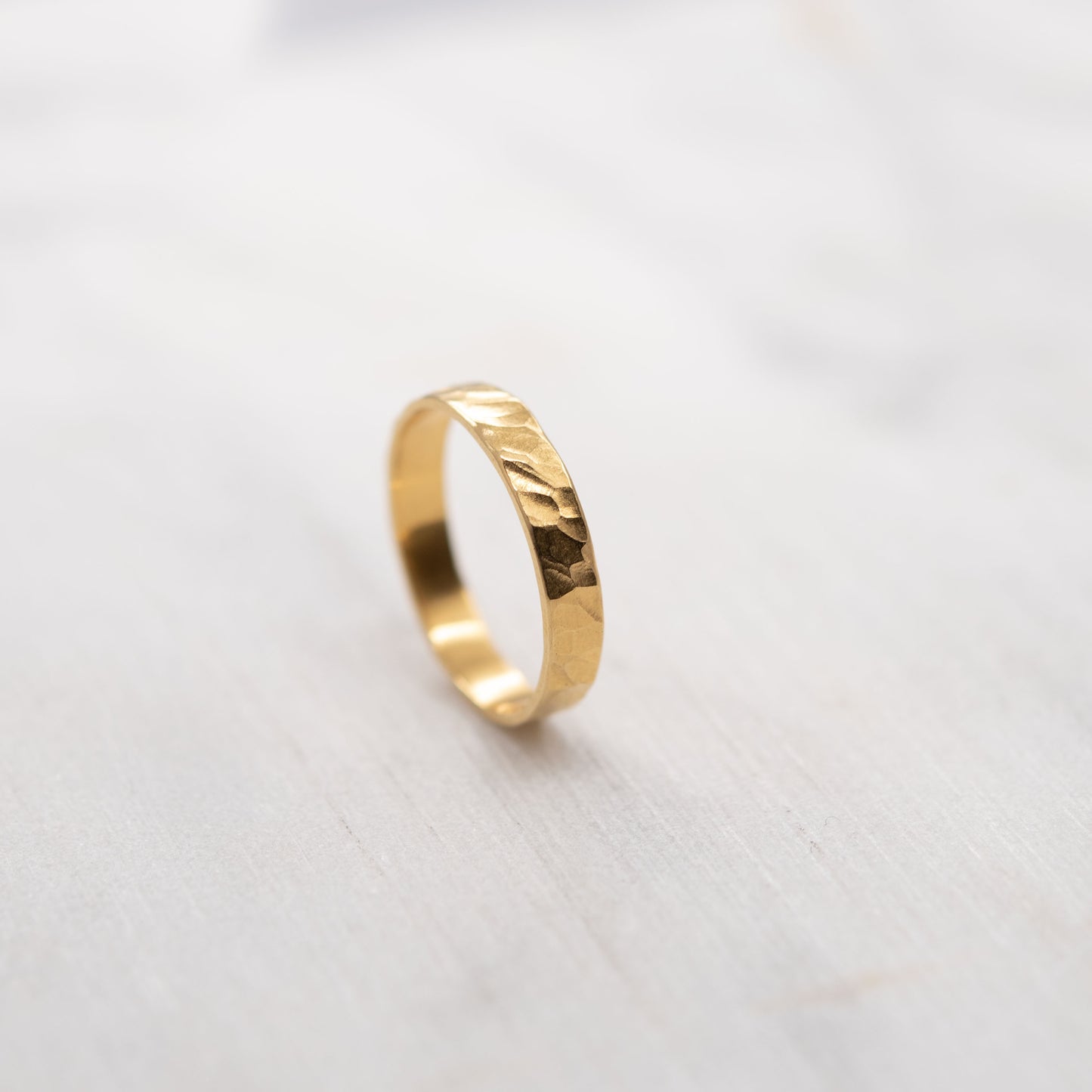 Bague martelée en vermeil or faite main, alliance artisanale photographiée sur fond clair minimaliste