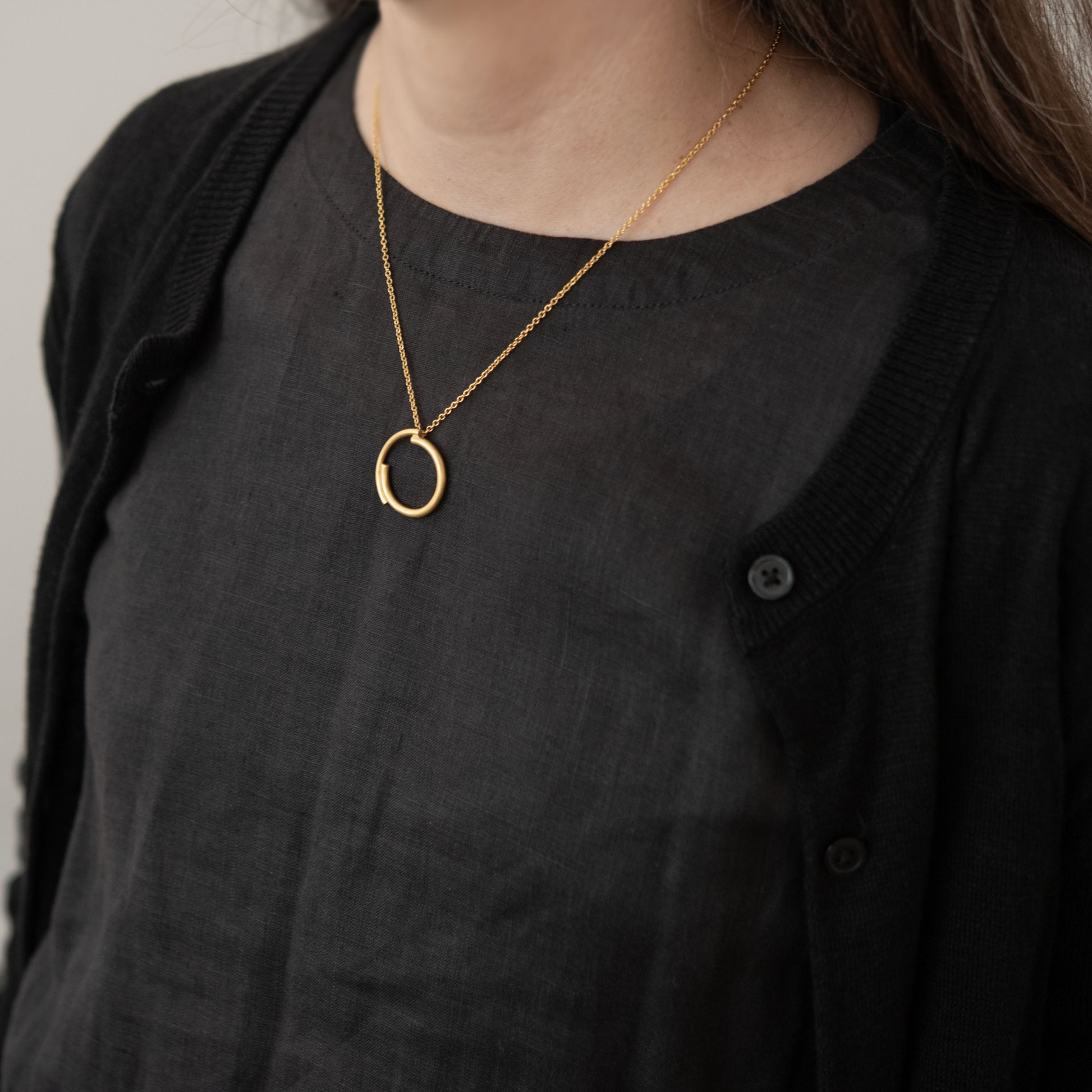 Femme portant un collier cercle en vermeil doré sur un haut noir en lin. Bijou parisien minimaliste pour une élégance au quotidien.