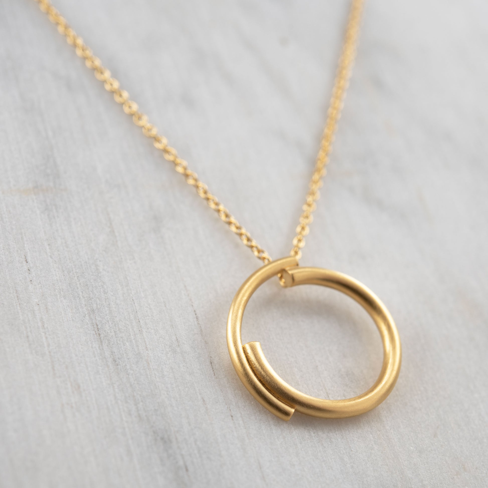 Vue rapprochée d’un collier cercle en vermeil sur fond clair, bijou minimaliste fait main à Paris.