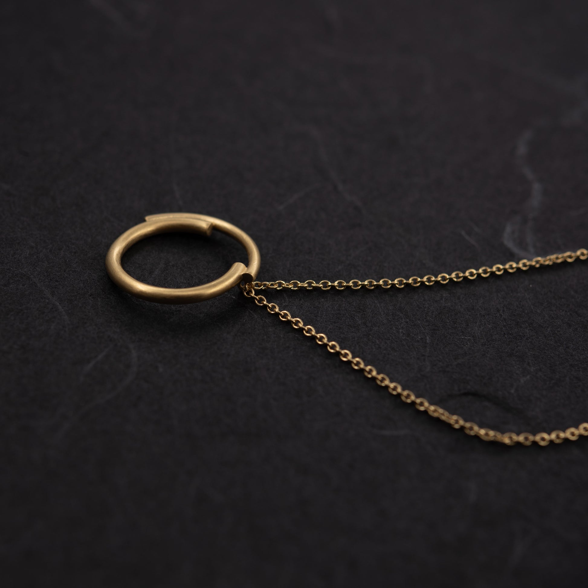 Collier cercle en vermeil photographié sur fond foncé, bijou moderne et artisanal, fabrication parisienne.