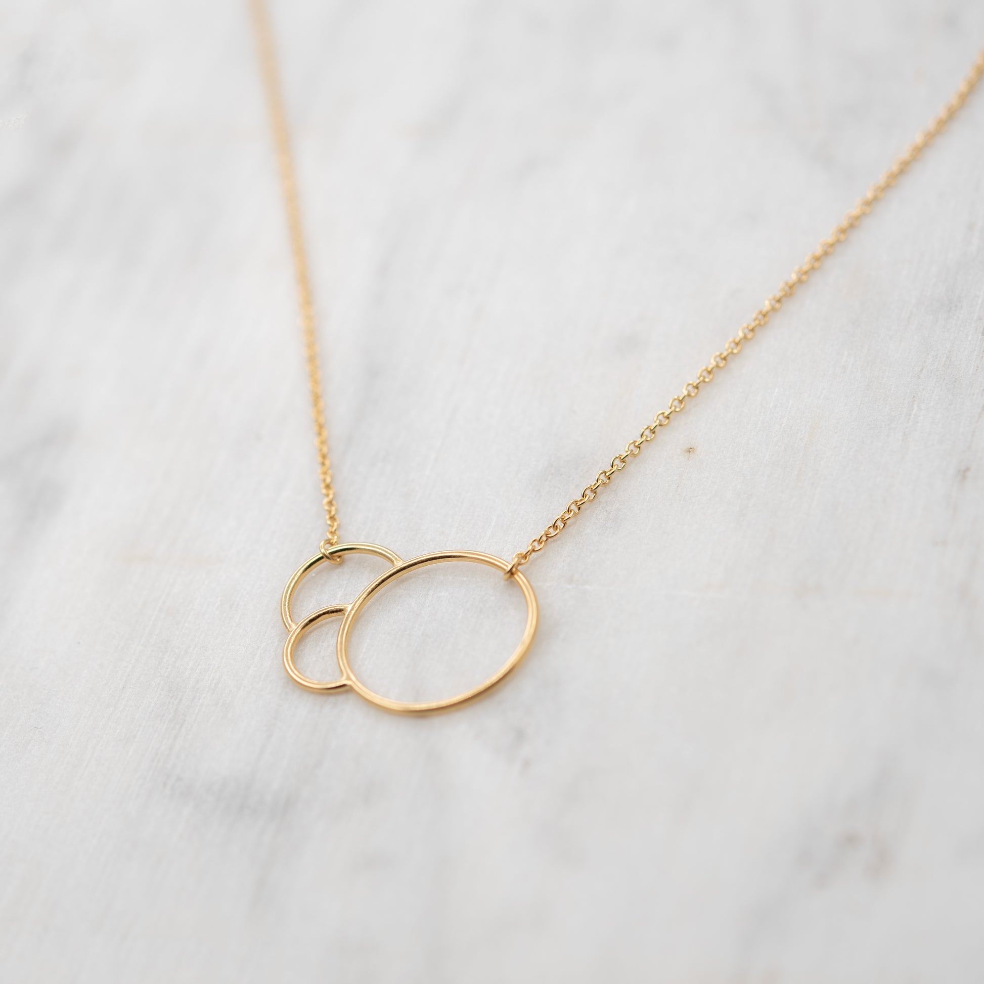 Collier minimaliste en vermeil avec cercles entrelacés sur fond marbré – bijou fait main à Paris