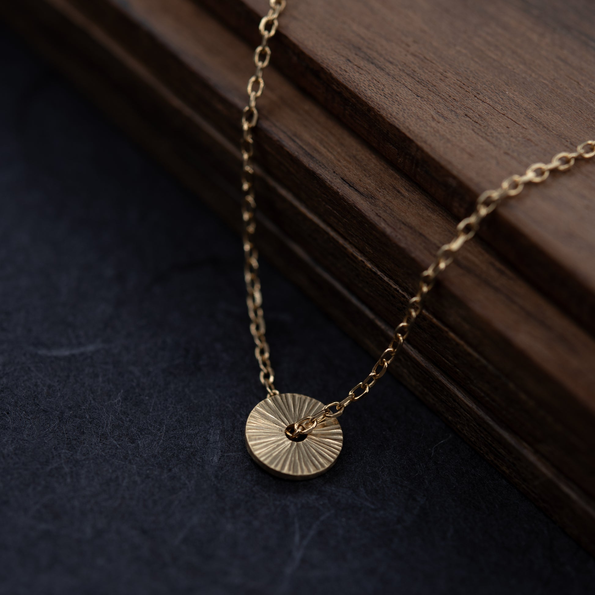 Collier Soleil en vermeil avec pendentif rond gravé à la main, photographié en gros plan pour révéler la texture lumineuse du bijou fabriqué à Paris.