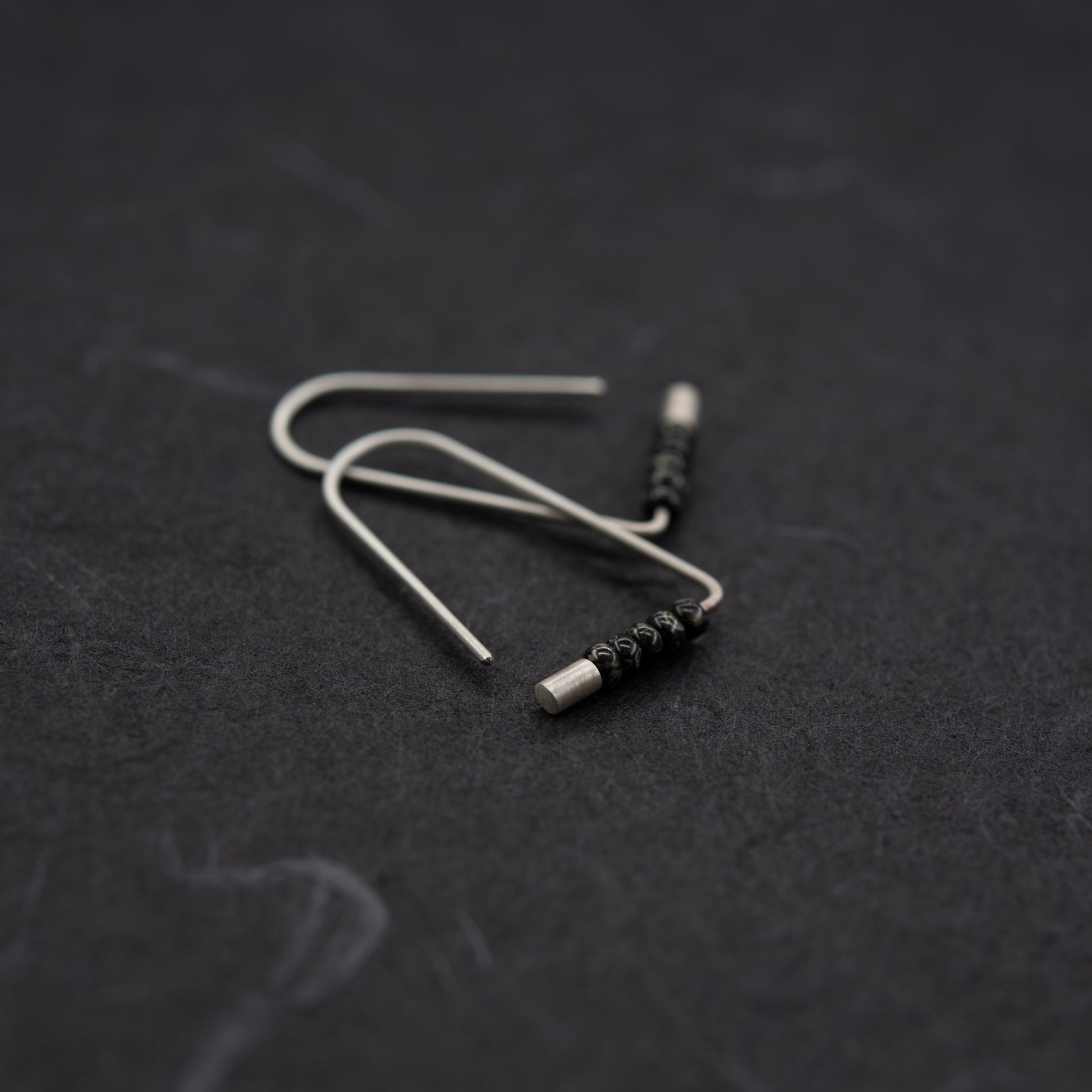 Vue rapprochée de creoles triangulaires en argent avec perles Miyuki, faites main à Paris.