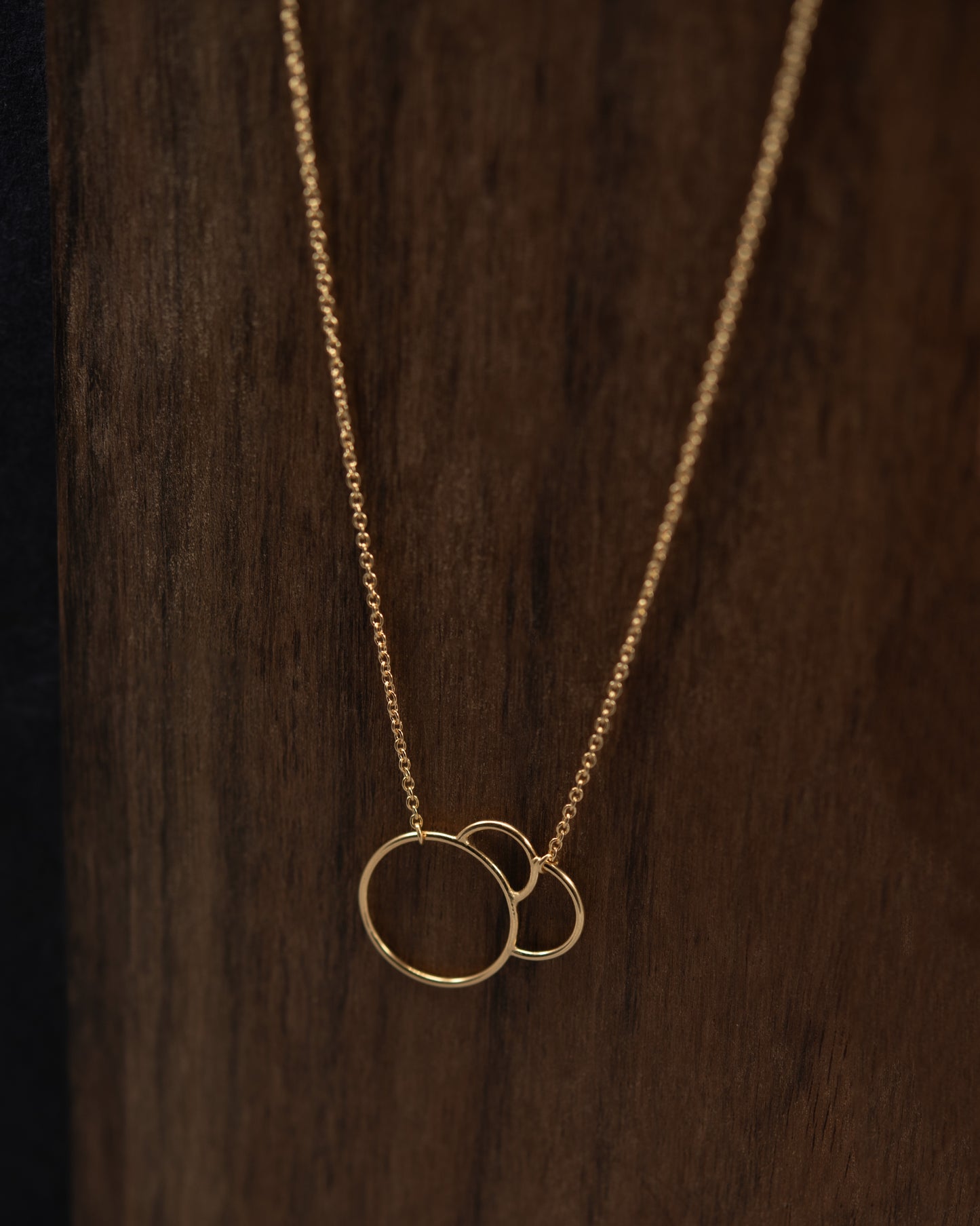 Gold necklace with interlaced rings on a wooden background