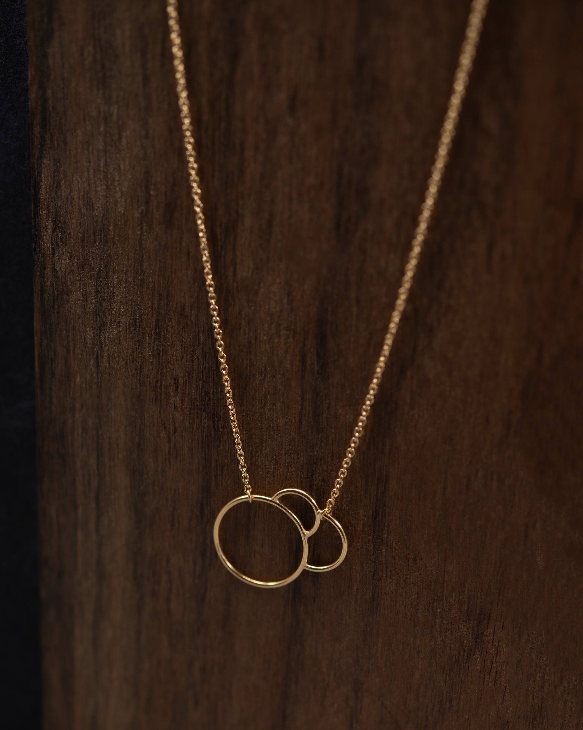 Gold necklace with interlaced rings on a wooden background