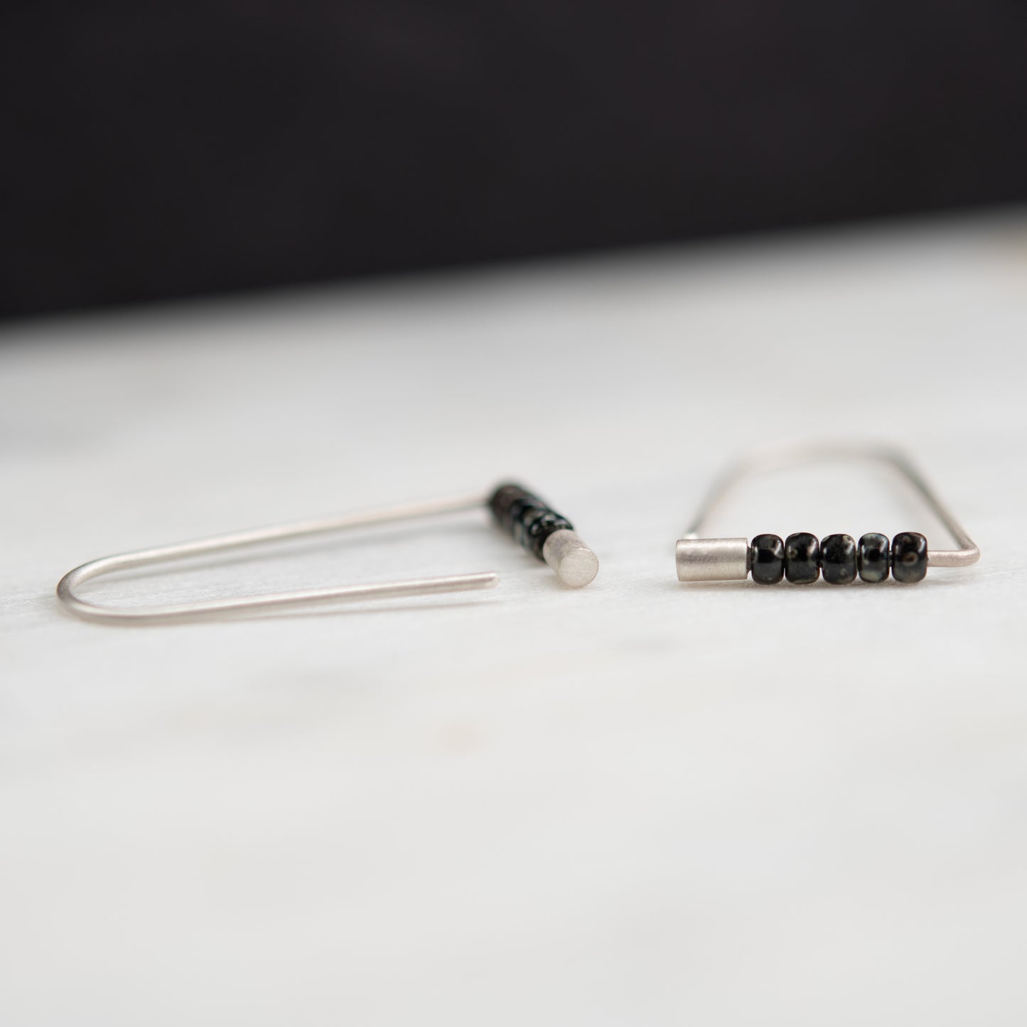 Handcrafted sterling silver triangle earrings with Miyuki beads in a close-up view.