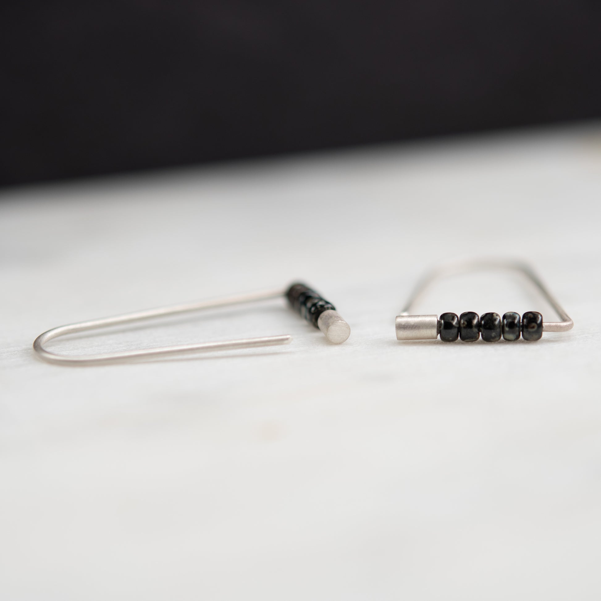 Handcrafted sterling silver triangle earrings with Miyuki beads in a close-up view.