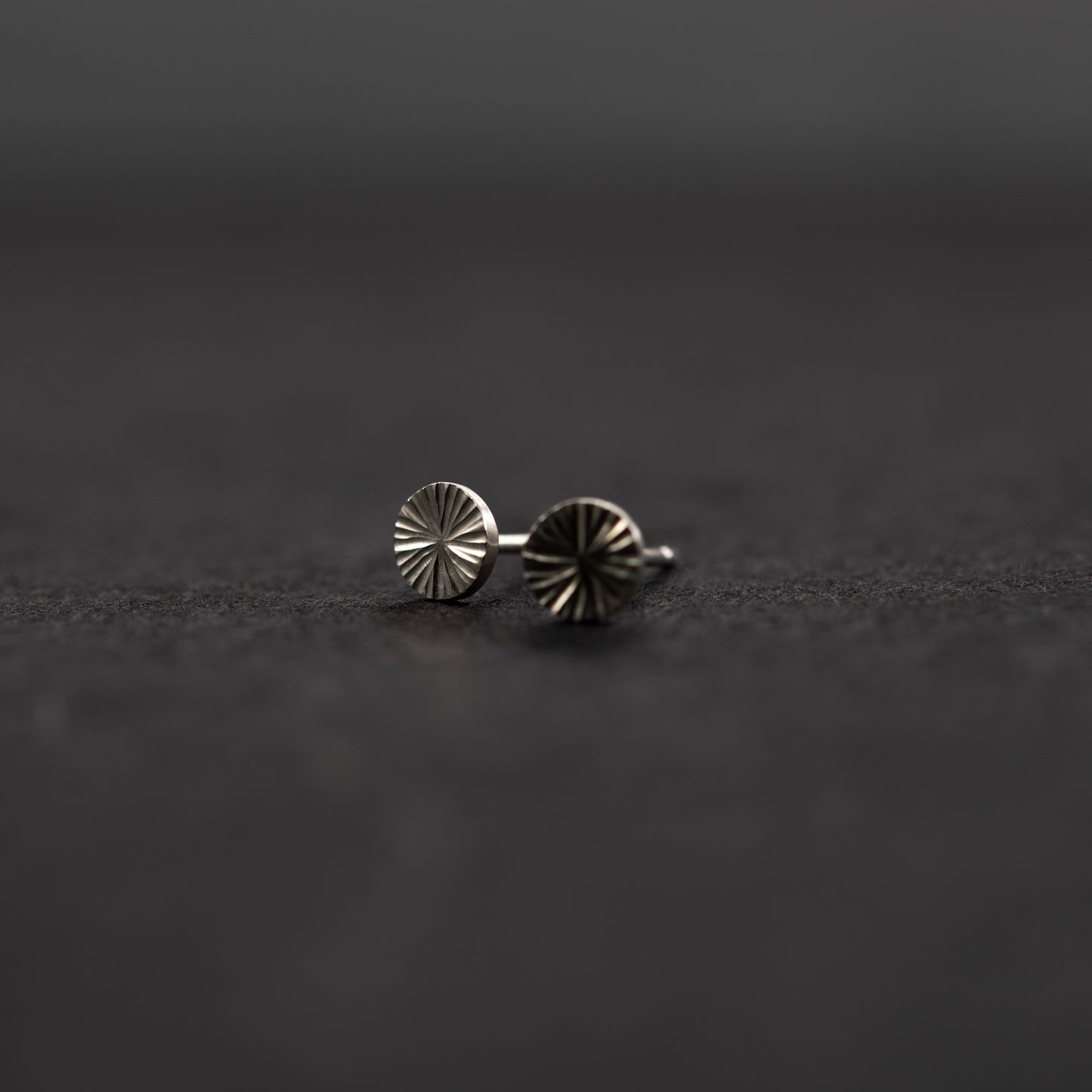 Handcrafted sterling silver round stud earrings, minimalist jewelry with quiet shine on a dark gray background