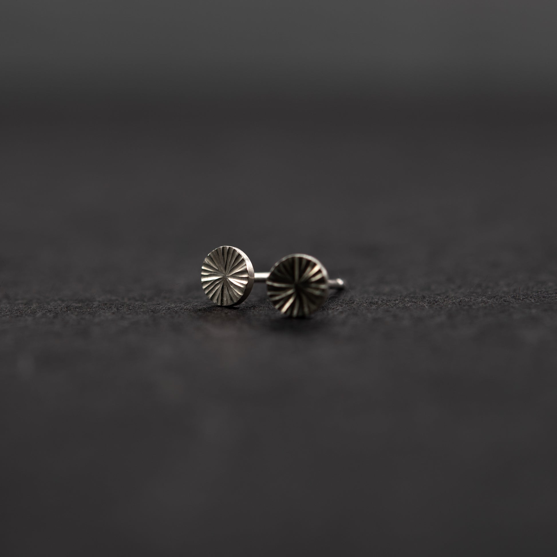 Handcrafted sterling silver round stud earrings, minimalist jewelry with quiet shine on a dark gray background