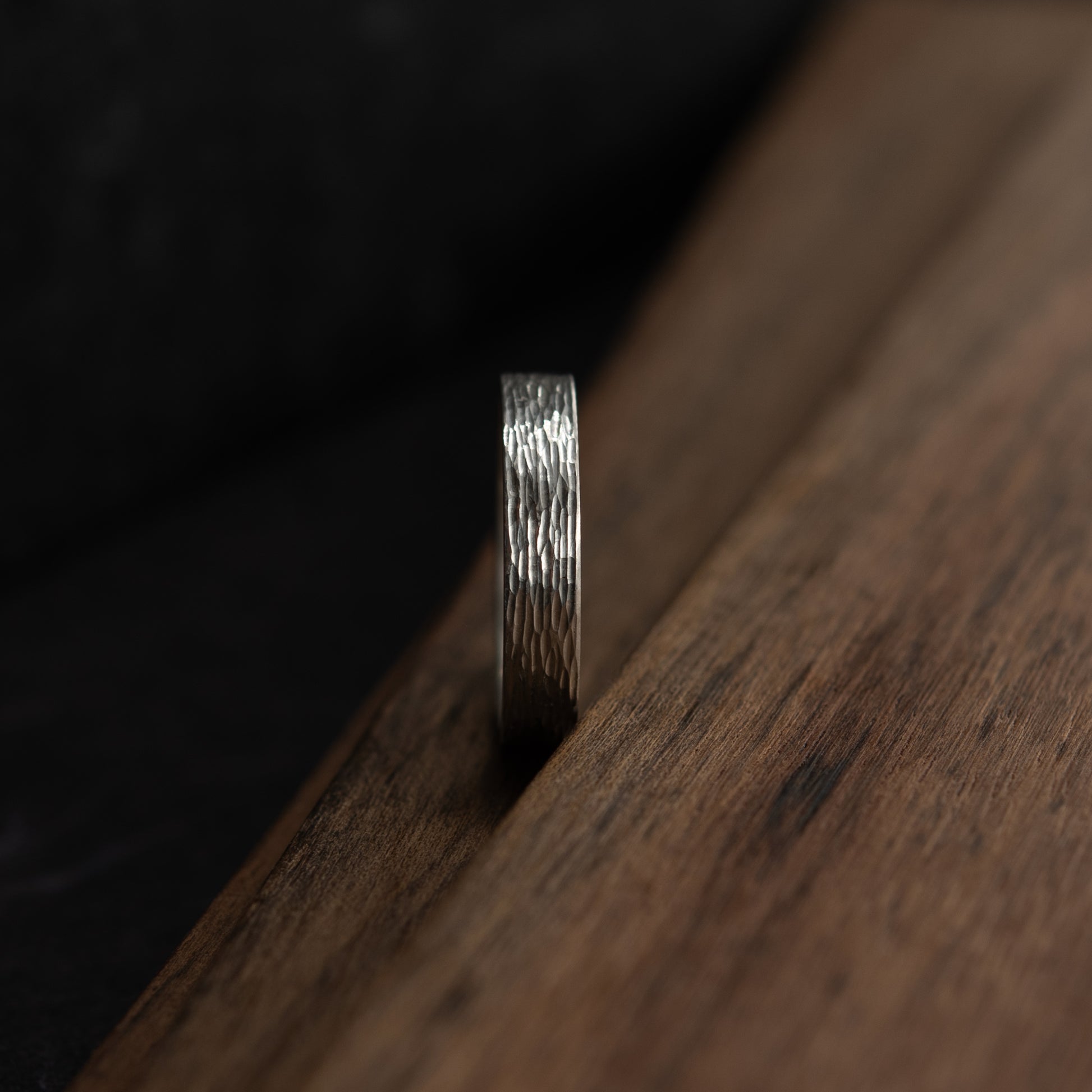 Vue de face de la bague Étincelles en argent montrant la texture gravée sur support en bois foncé.