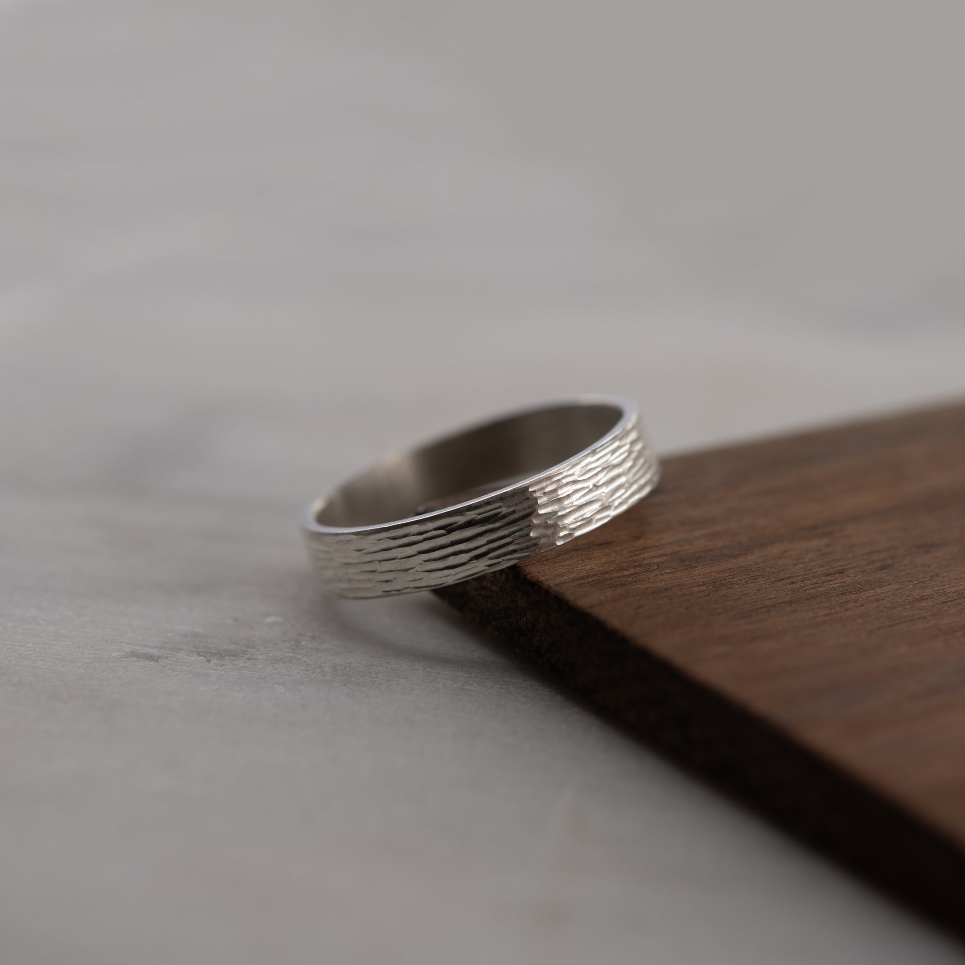 Gros plan de la bague artisanale en argent massif avec texture gravée lumineuse sur fond claire