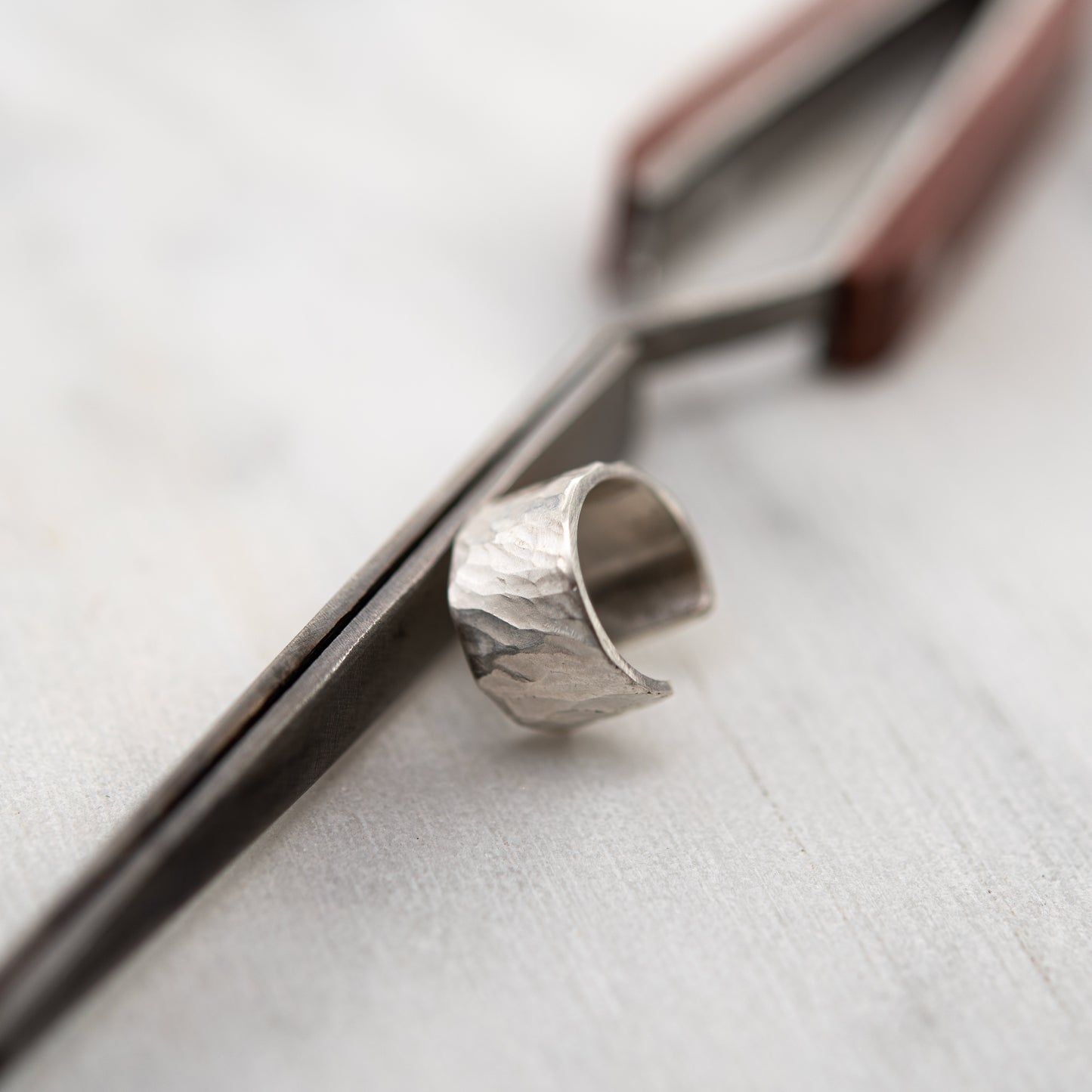 Close-up of hammered sterling silver ear cuff, handcrafted beside jeweler’s tool in our Paris studio