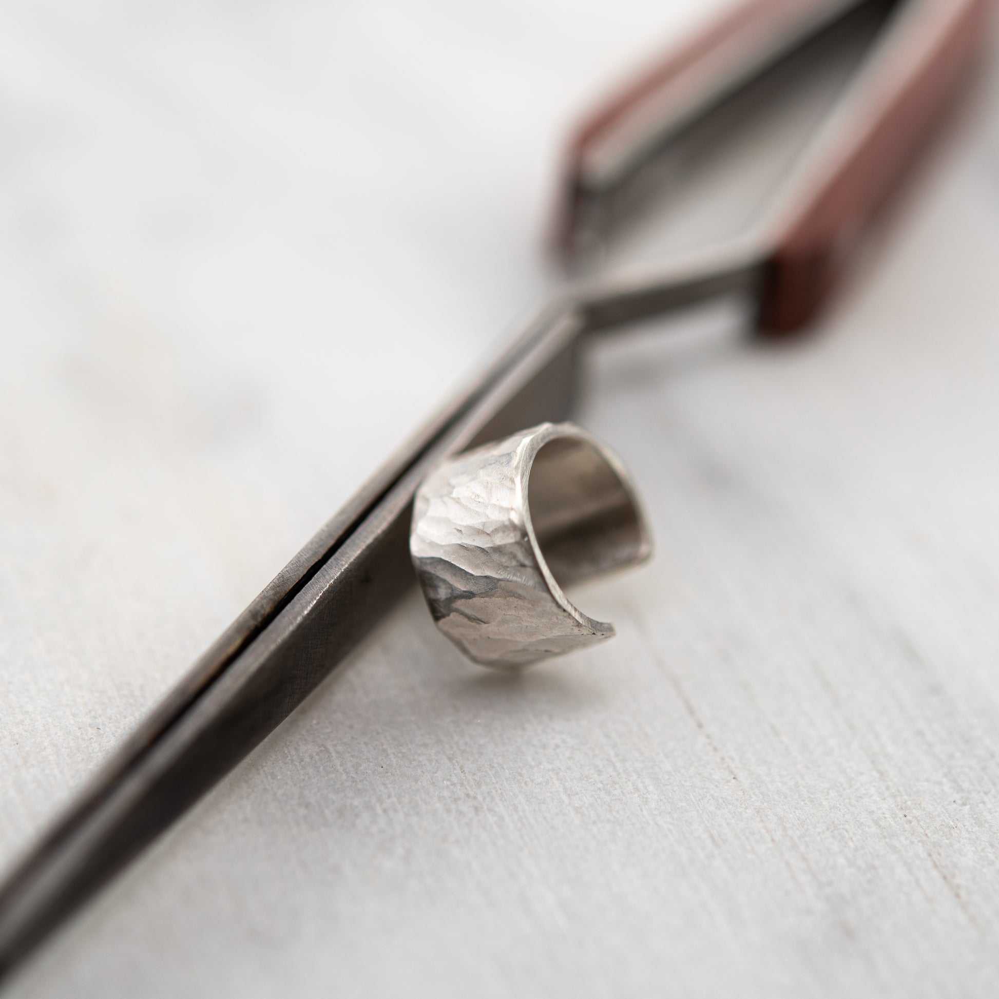 Close-up of hammered sterling silver ear cuff, handcrafted beside jeweler’s tool in our Paris studio