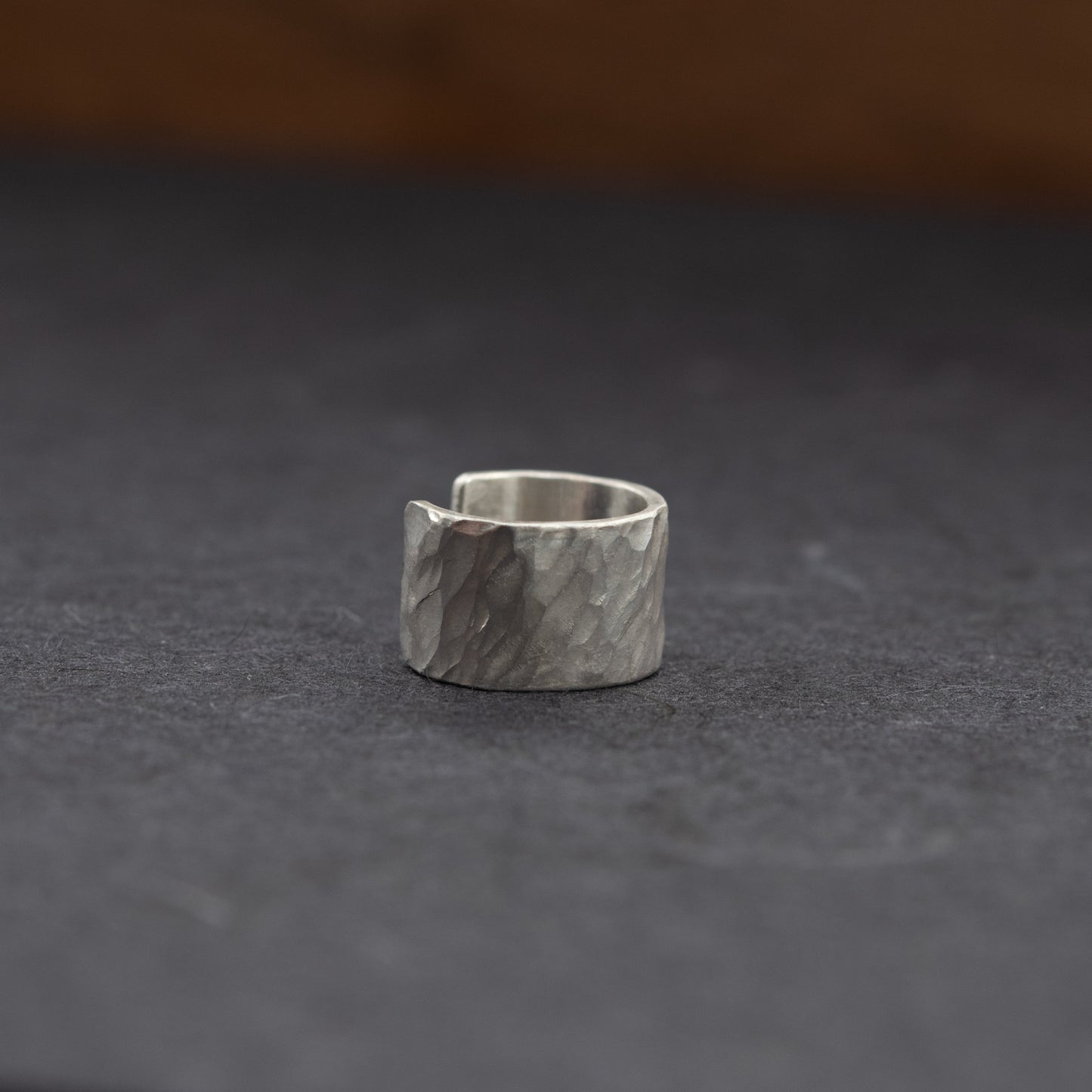 Vue trois-quarts de la bague d’oreille en argent massif martelé, modèle ouvert sans piercing sur fond sombre.