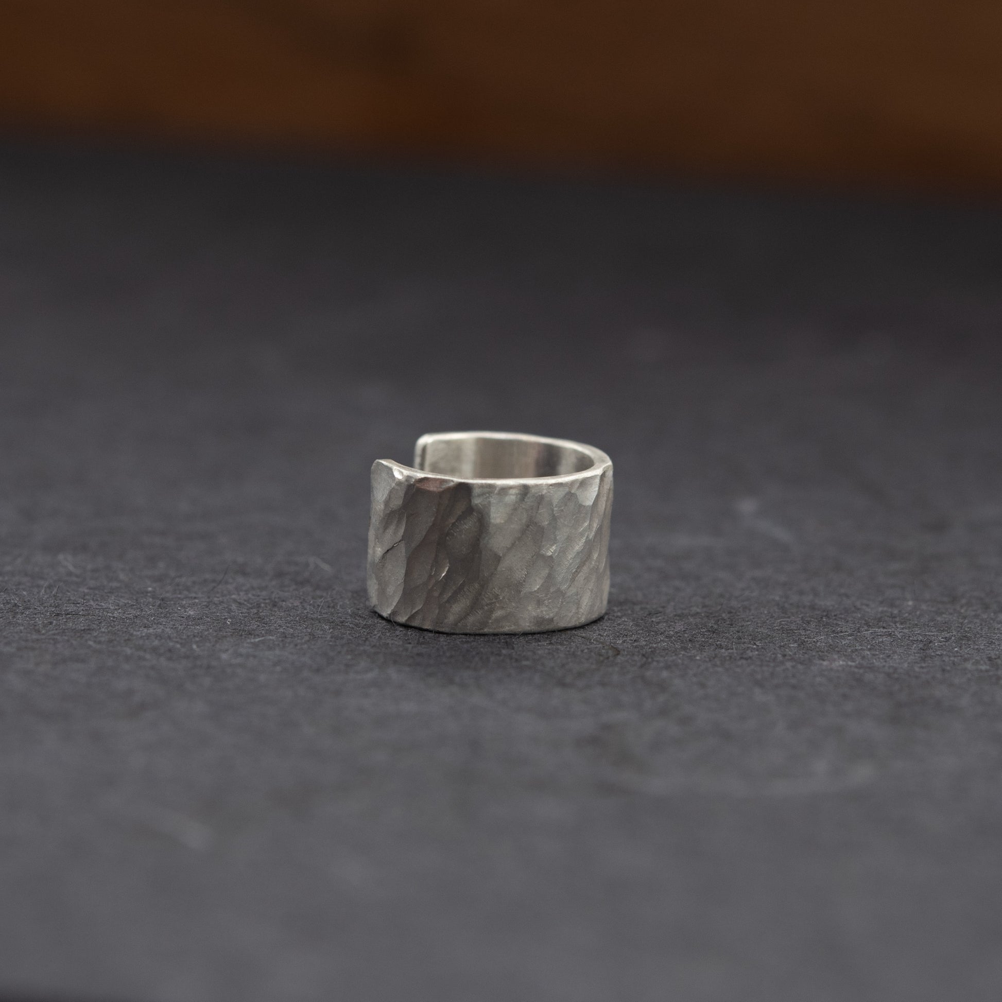 Vue trois-quarts de la bague d’oreille en argent massif martelé, modèle ouvert sans piercing sur fond sombre.