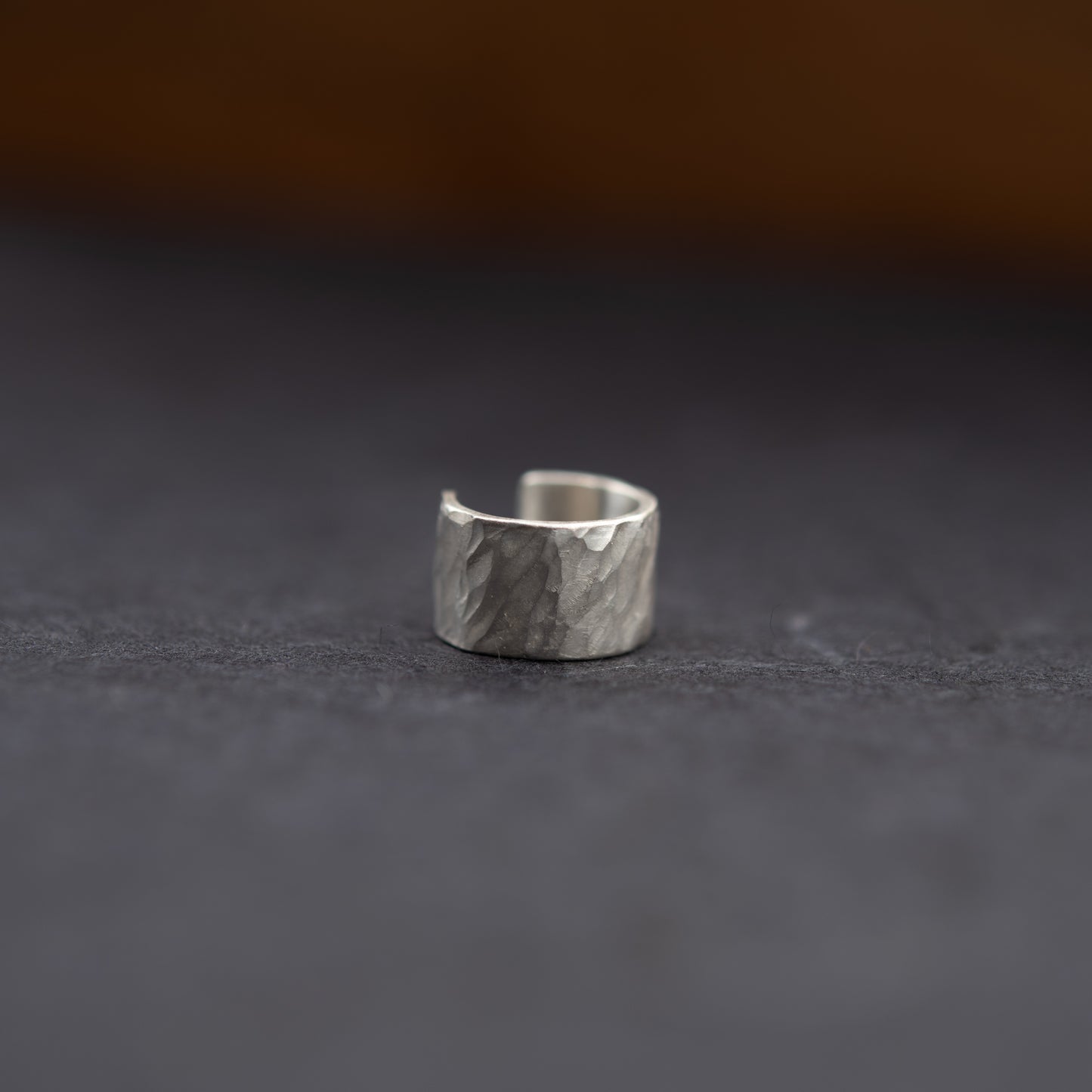 Gros plan de la bague d’oreille en argent massif, texture martelée artisanale sur fond sombre