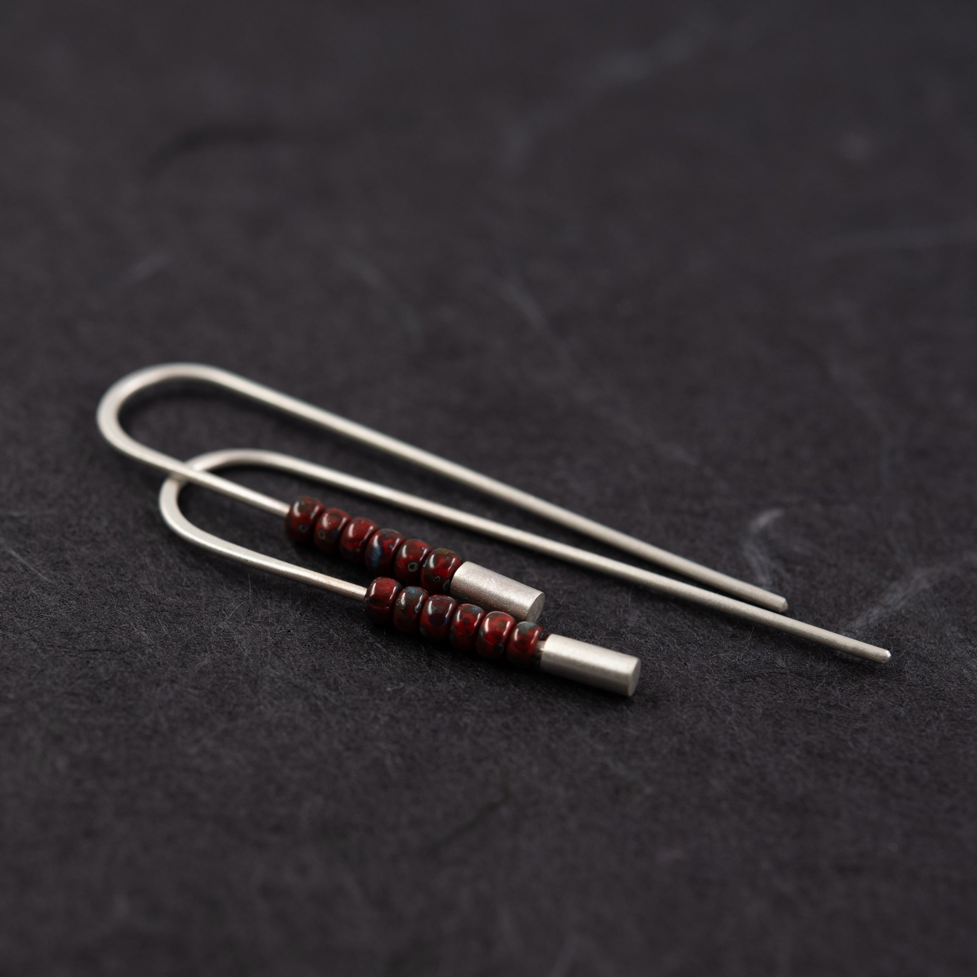 Vue en diagonale des boucles d’oreilles traversantes en argent 925 et perles Miyuki rouge profond 