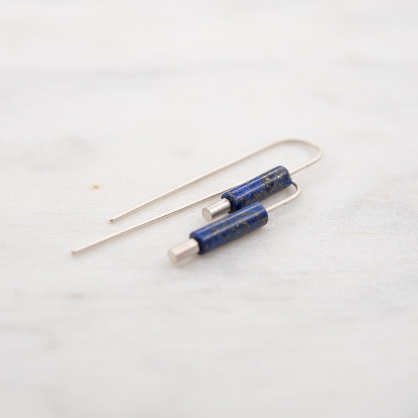 vue proche des boucles oreilles argent lapis lazuli pendantes minimalistes sur fond clair