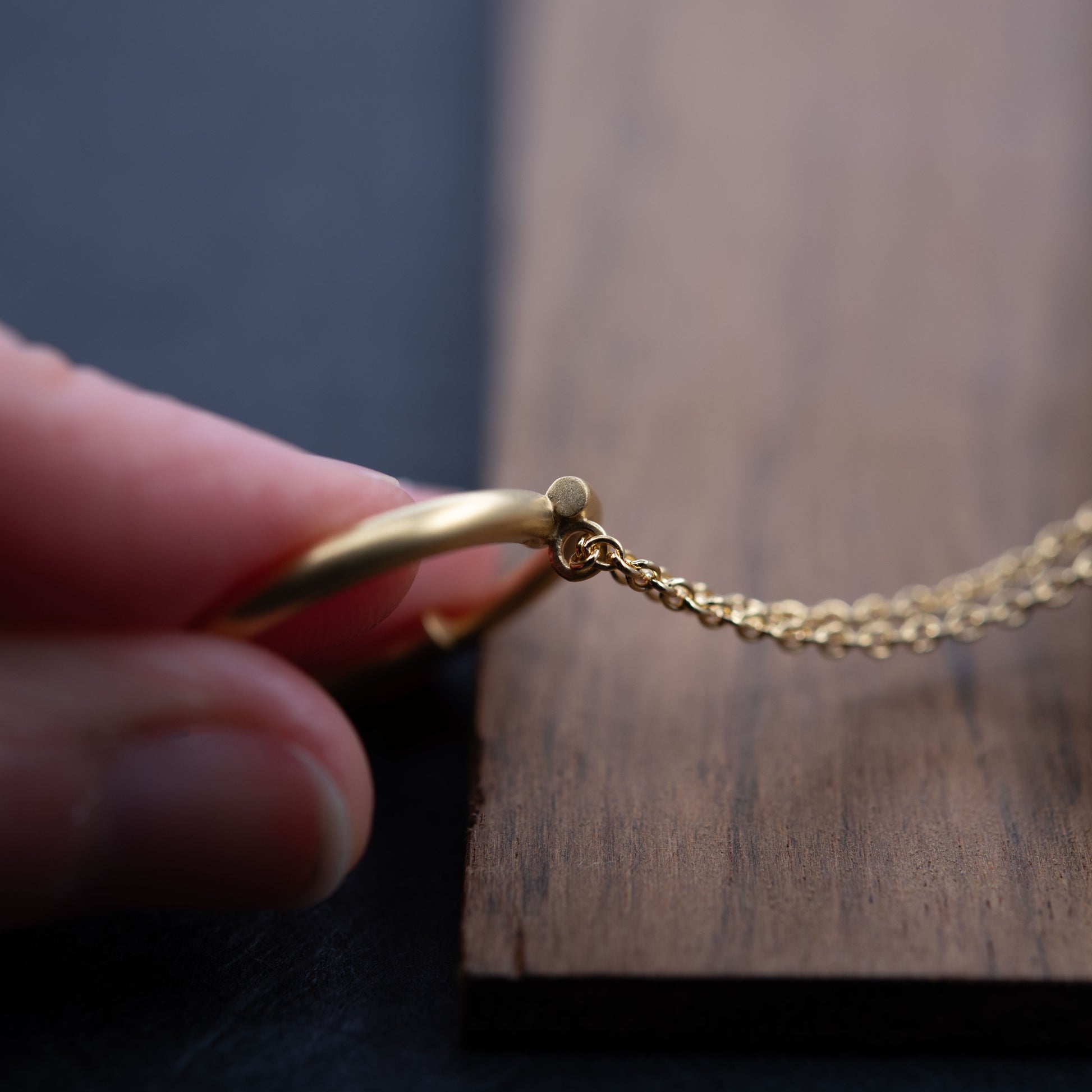 Vue arrière du collier cercle en vermeil avec détail de l'accroche, photographié sur fond noir. Bijou doré minimaliste fait main à Paris.