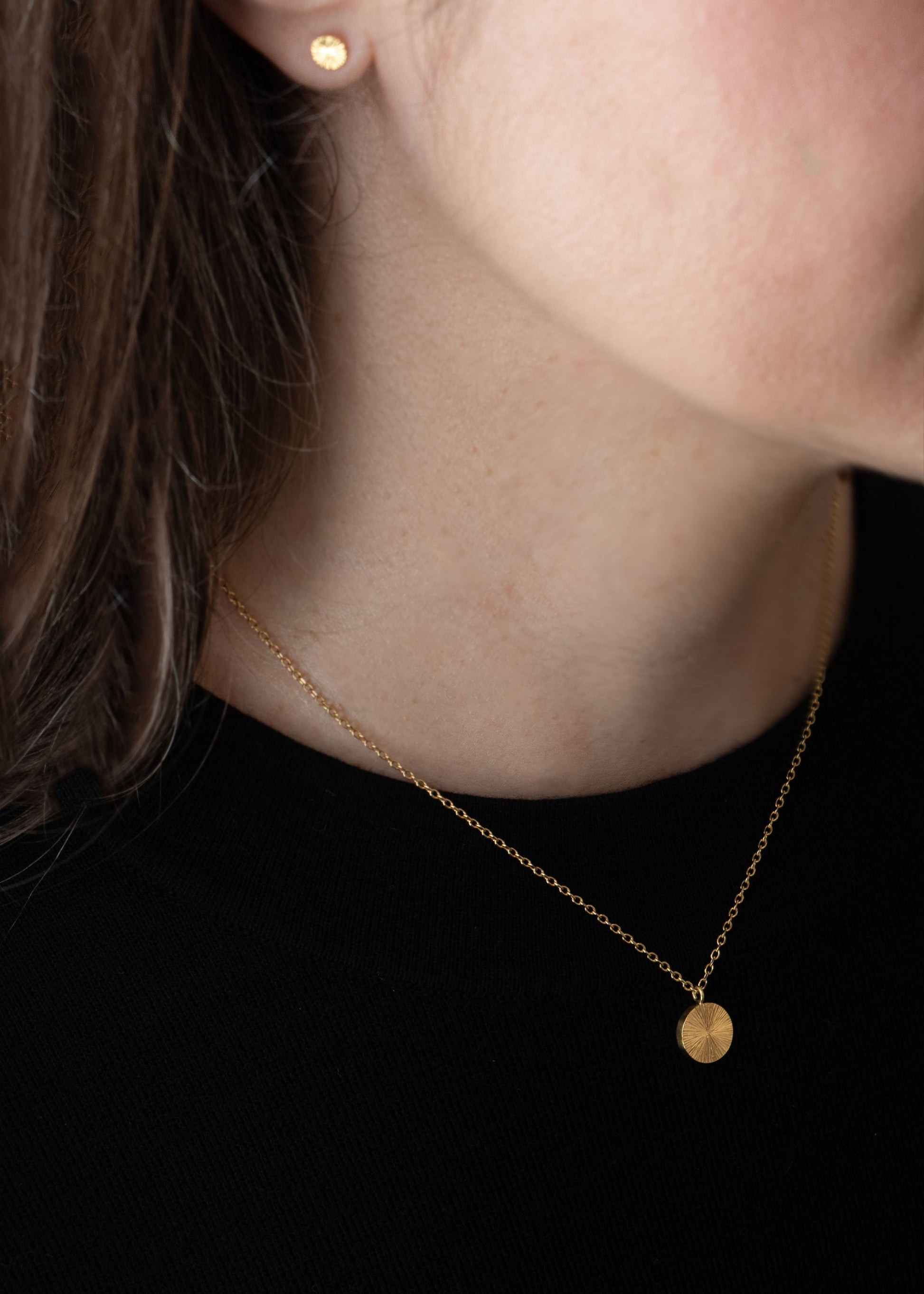 8. Modèle portant collier médaille éclat de soleil en or gravé à la main, bijou artisanal élégant et discret de Paris.