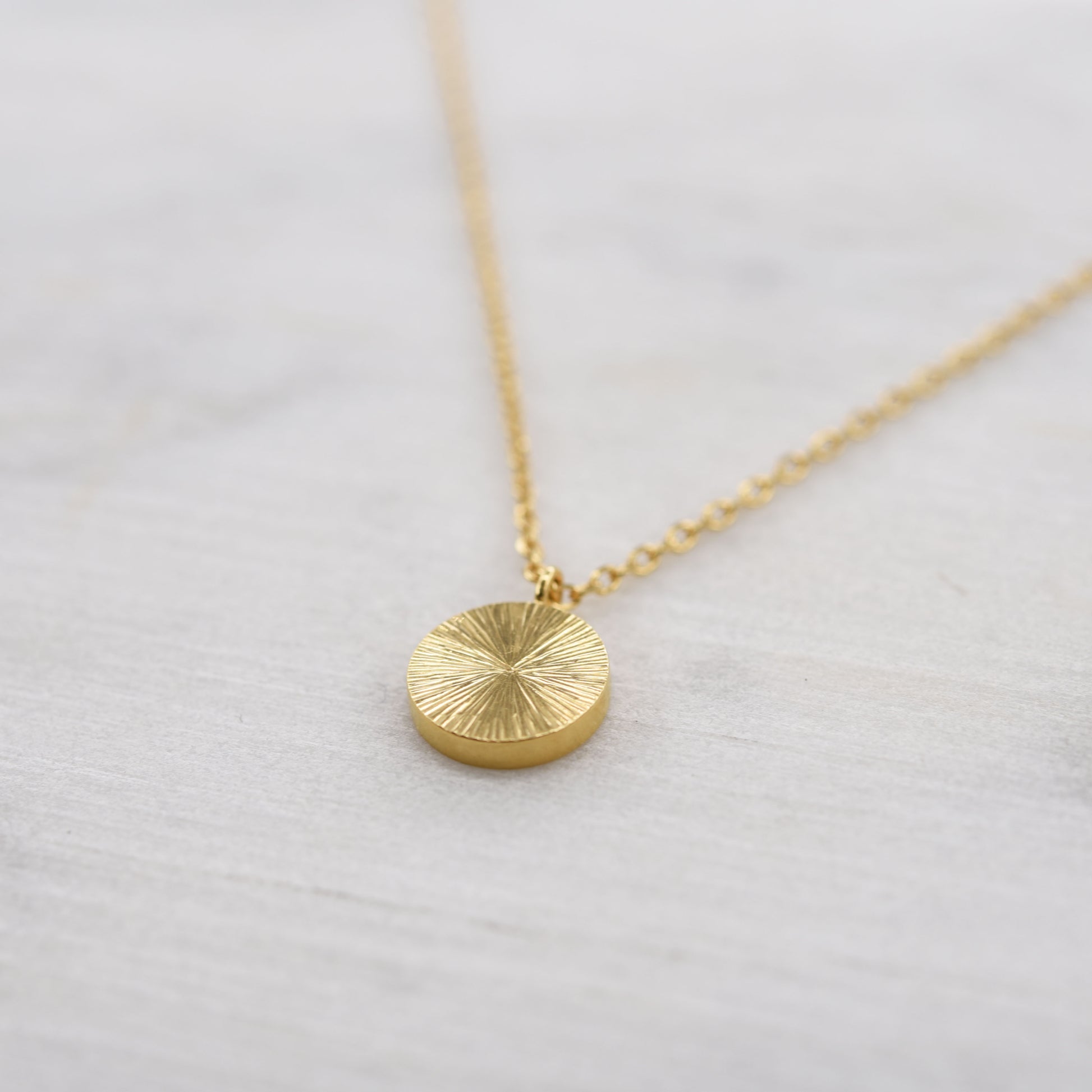 Vue de côté collier pendentif lumineux comme un éclat de soleil en vermeil doré. Bijou minimaliste artisanal de Paris. 