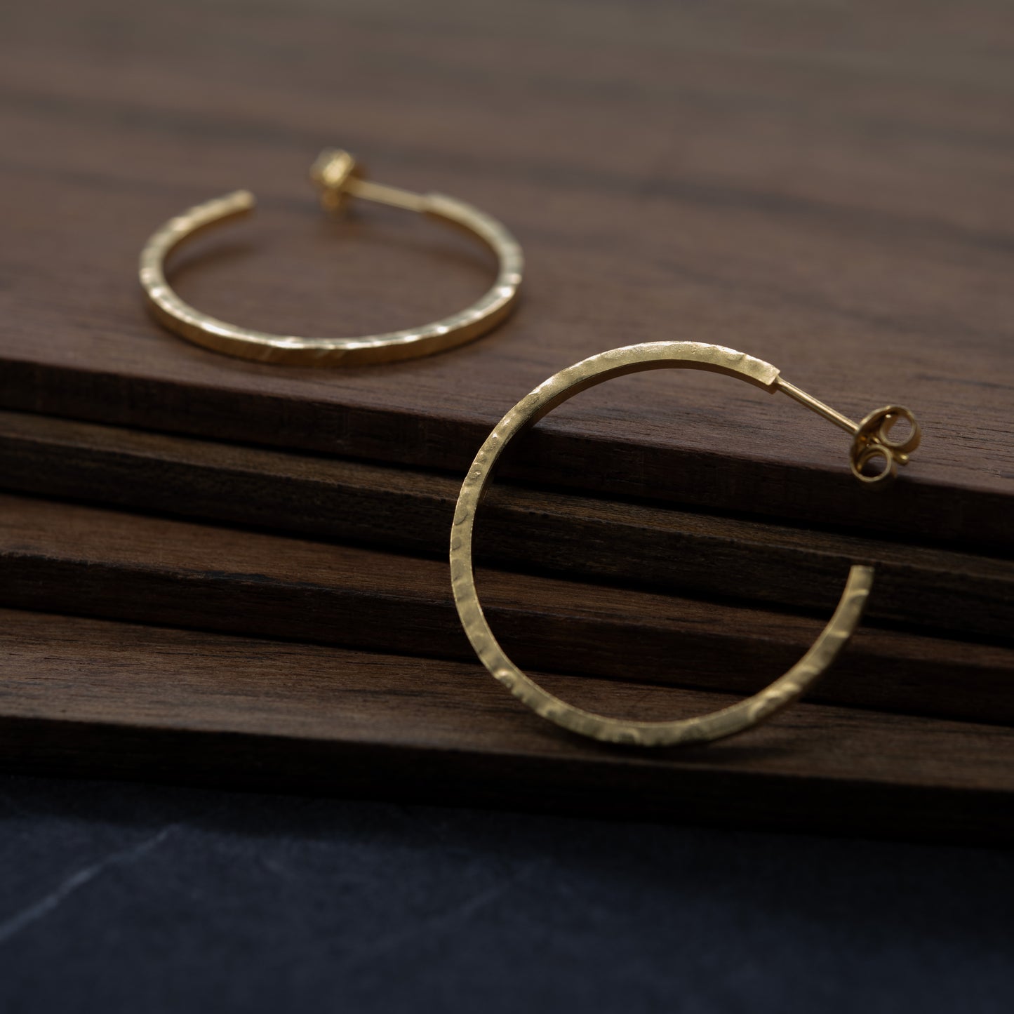 Créoles dorées martelées sur fond de bois – bijou artisanal parisien minimaliste