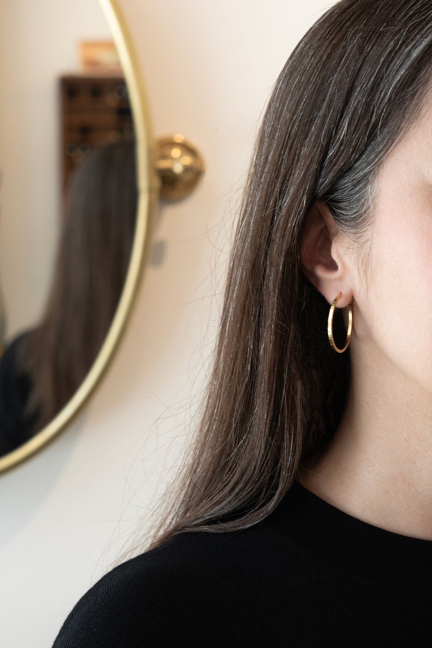 Gros plan d'une personne portant des boucles d'oreilles en or avec un fond flou– boucles d’oreilles dorées élégantes