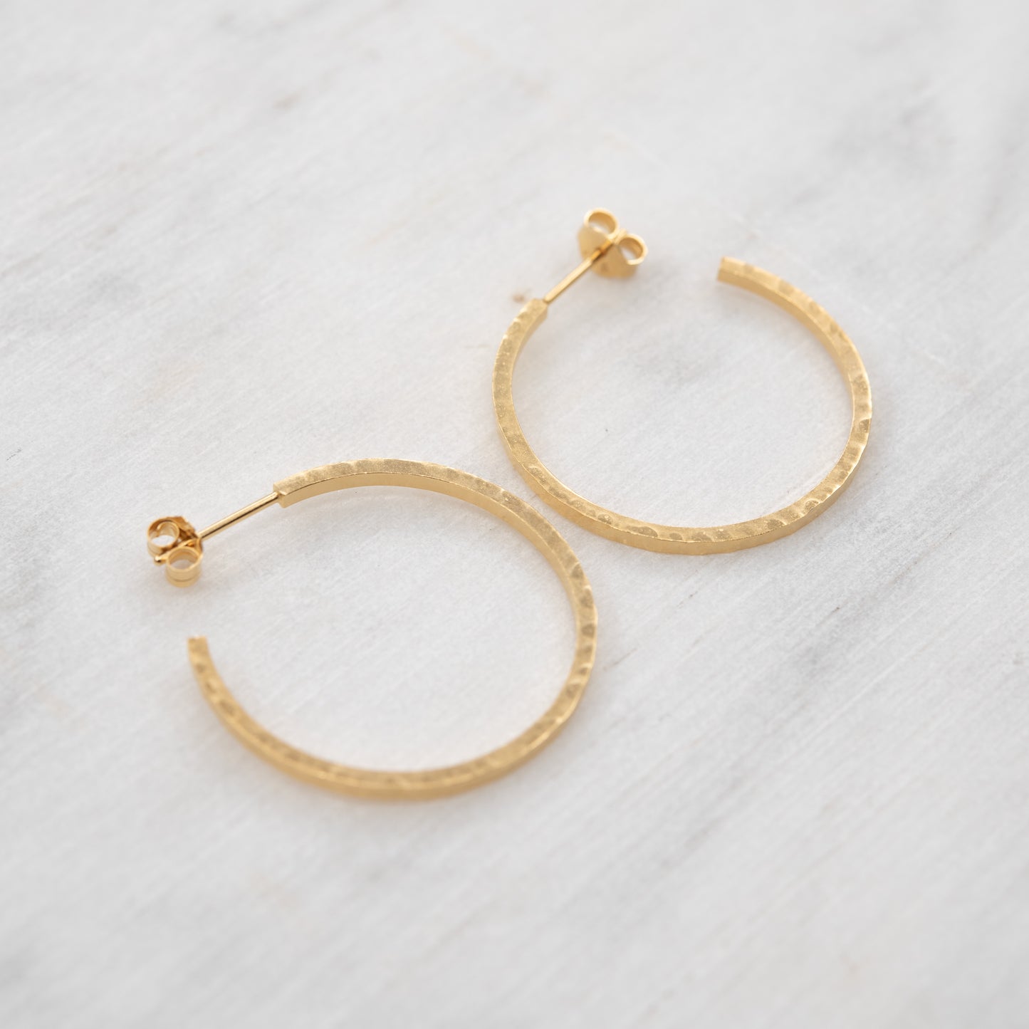 Grandes créoles martelées en vermeil doré à l’or 24k sur un fond claire. faites main à Paris – AgJc