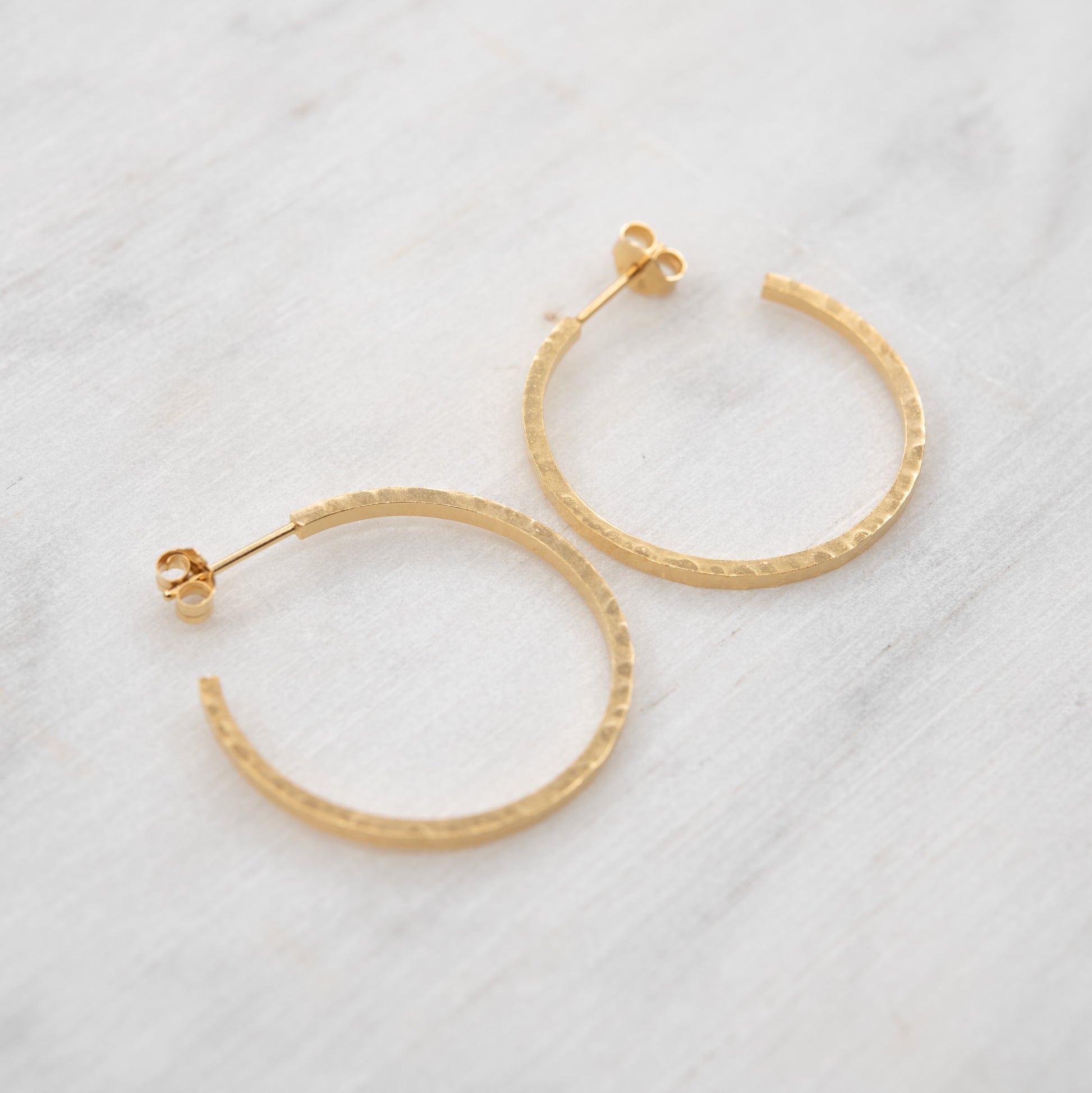 Grandes créoles martelées en vermeil doré à l’or 24k sur un fond claire. faites main à Paris – AgJc