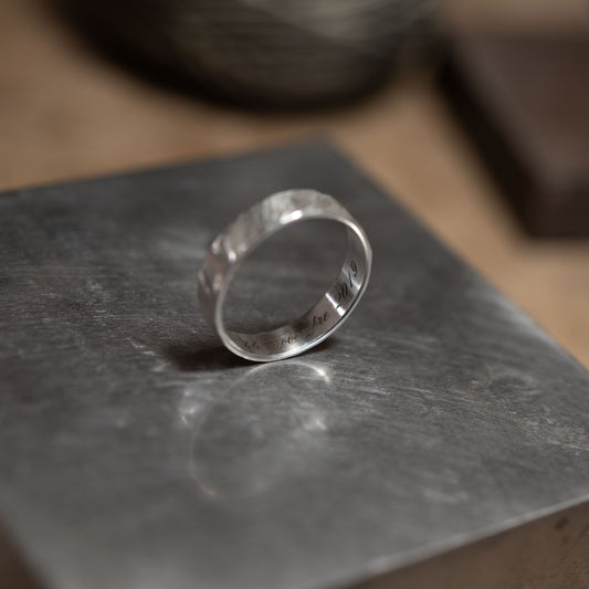 Vue rapprochée de l’intérieur d’une bague en argent, mettant en valeur une gravure personnalisée en lettres anglaises, exemple du service de gravure proposé pour les bagues artisanales AgJc.